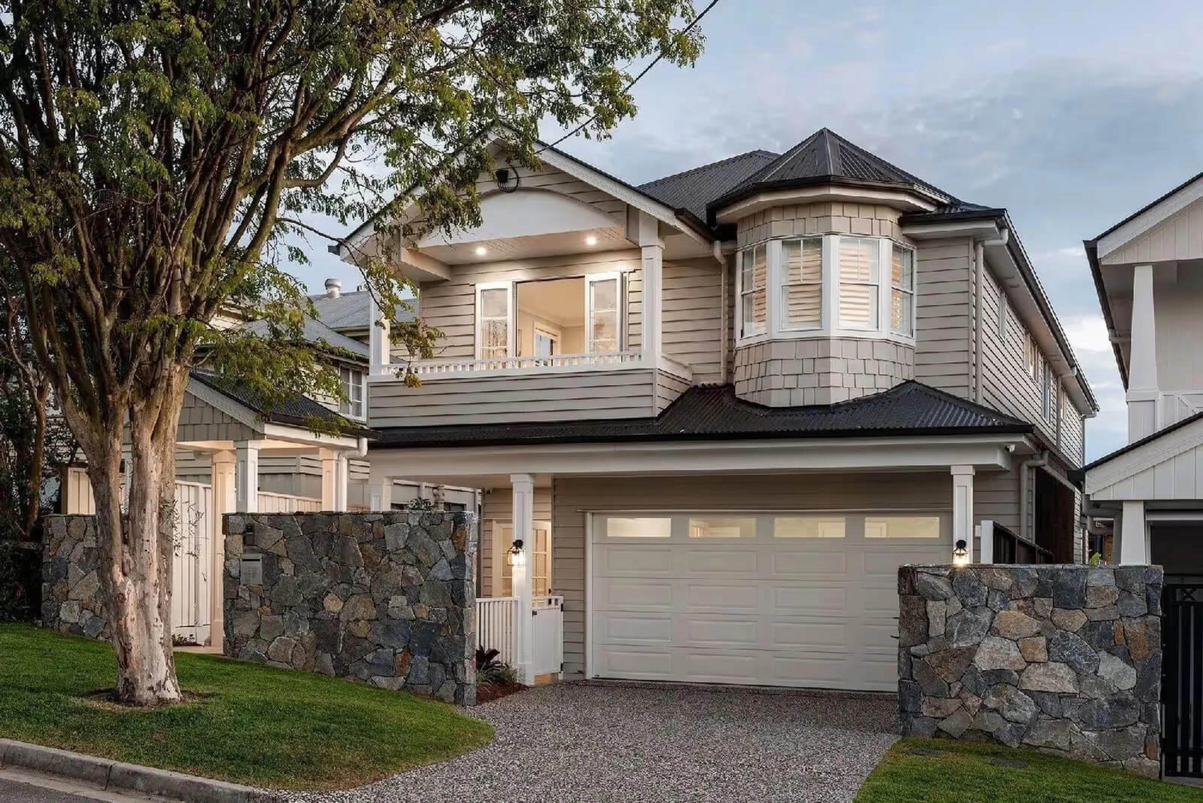 Two storey weatherboard home with garage and stone fence