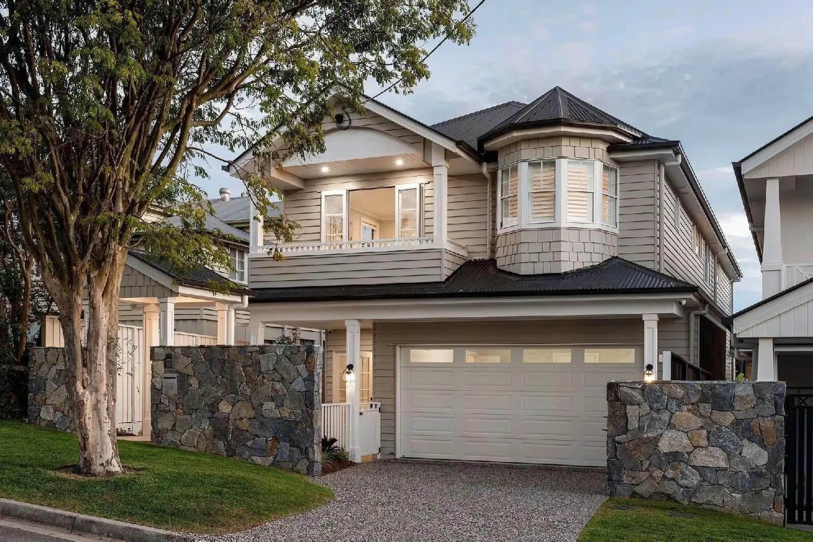 Two storey weatherboard home with garage and stone fence