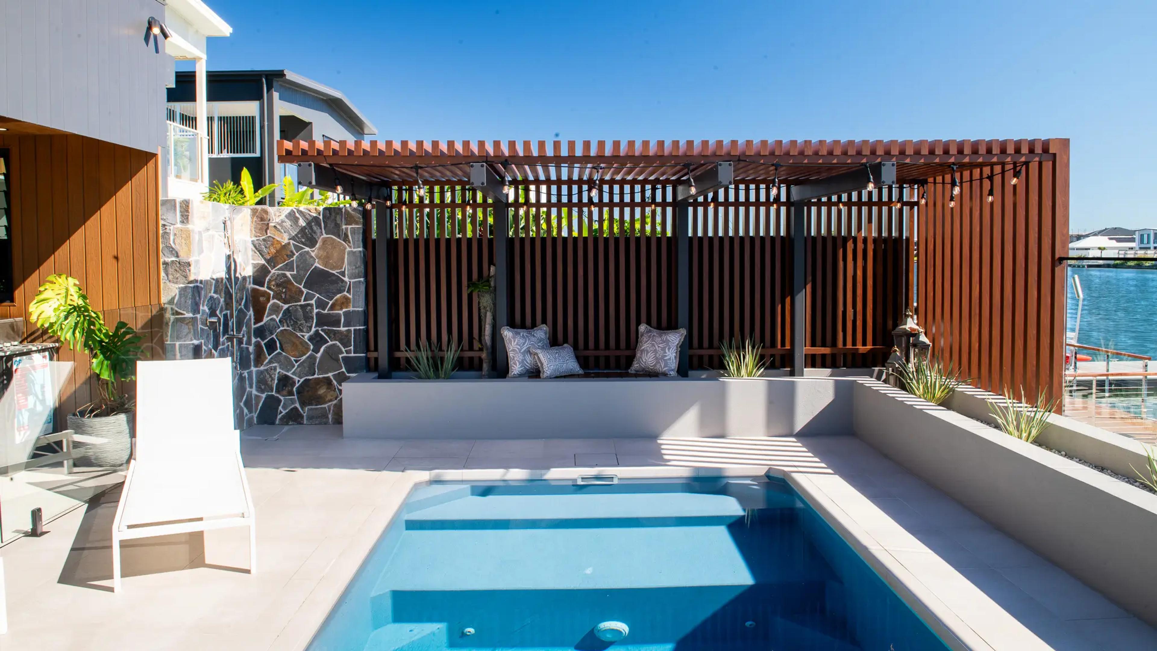 Waterfront pool with timber cabana and stone wall