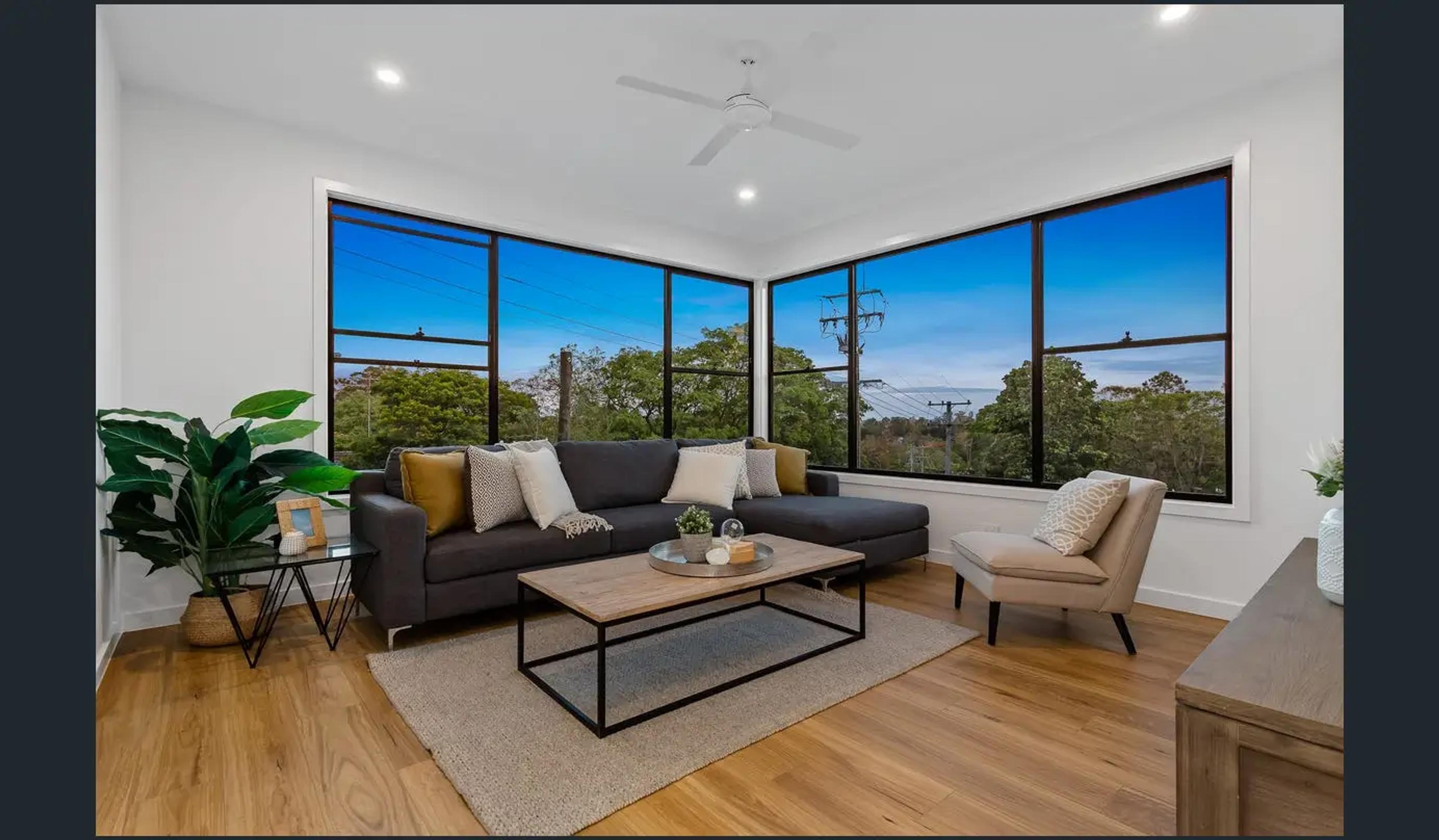 Living room with corner windows framing leafy treetop views