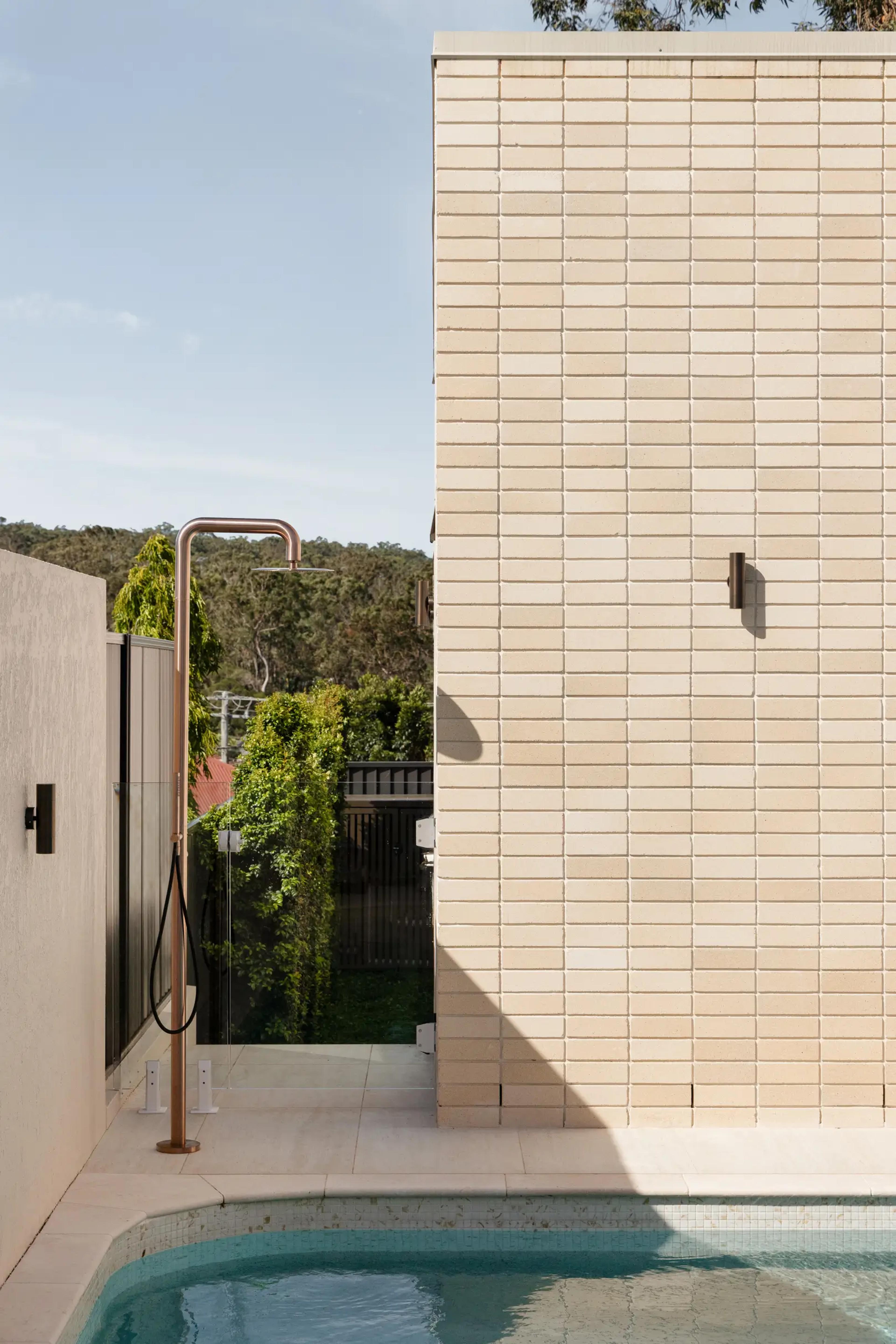 Brick pool house wall with copper outdoor shower and gate