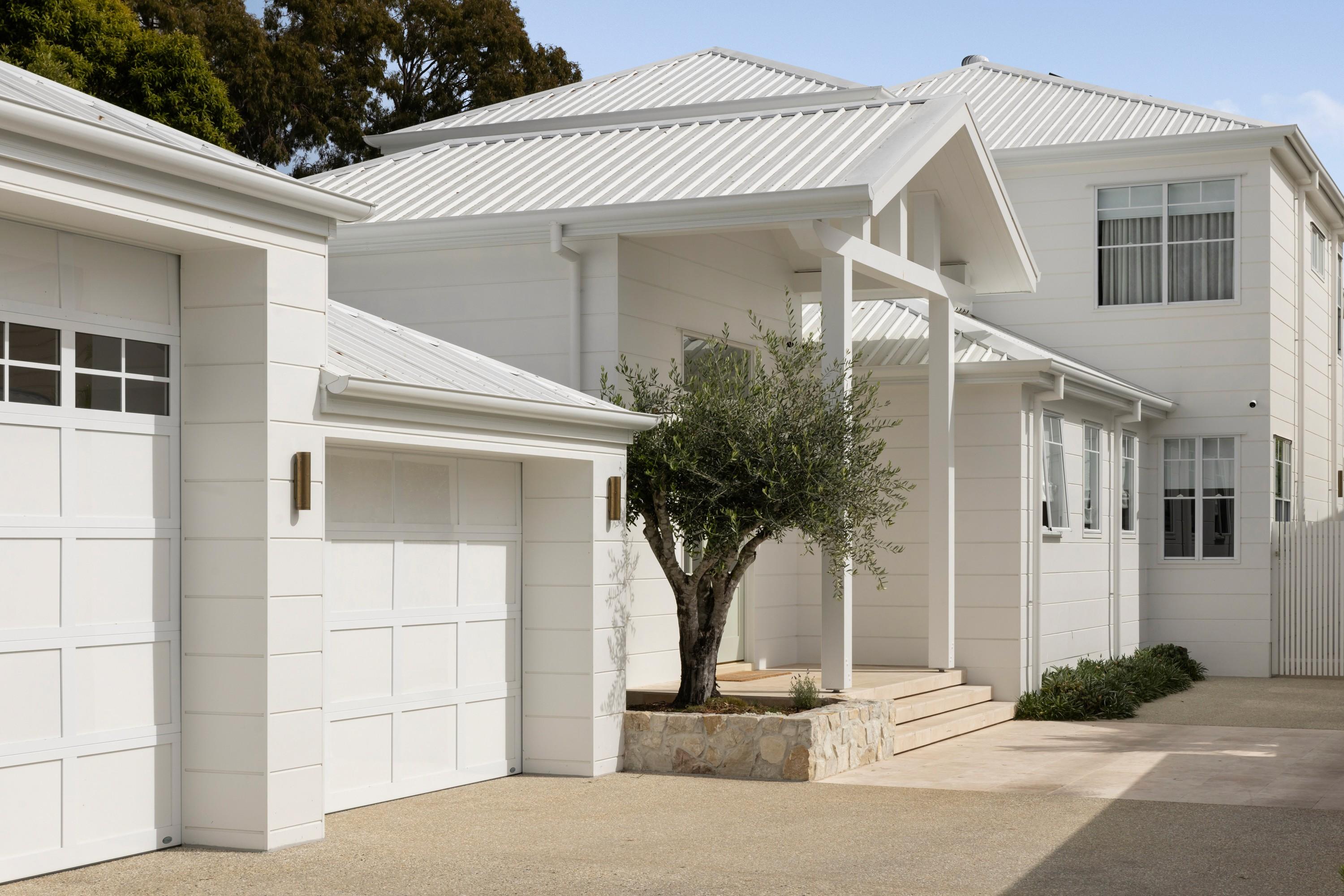 White weatherboard home front with double garages and driveway