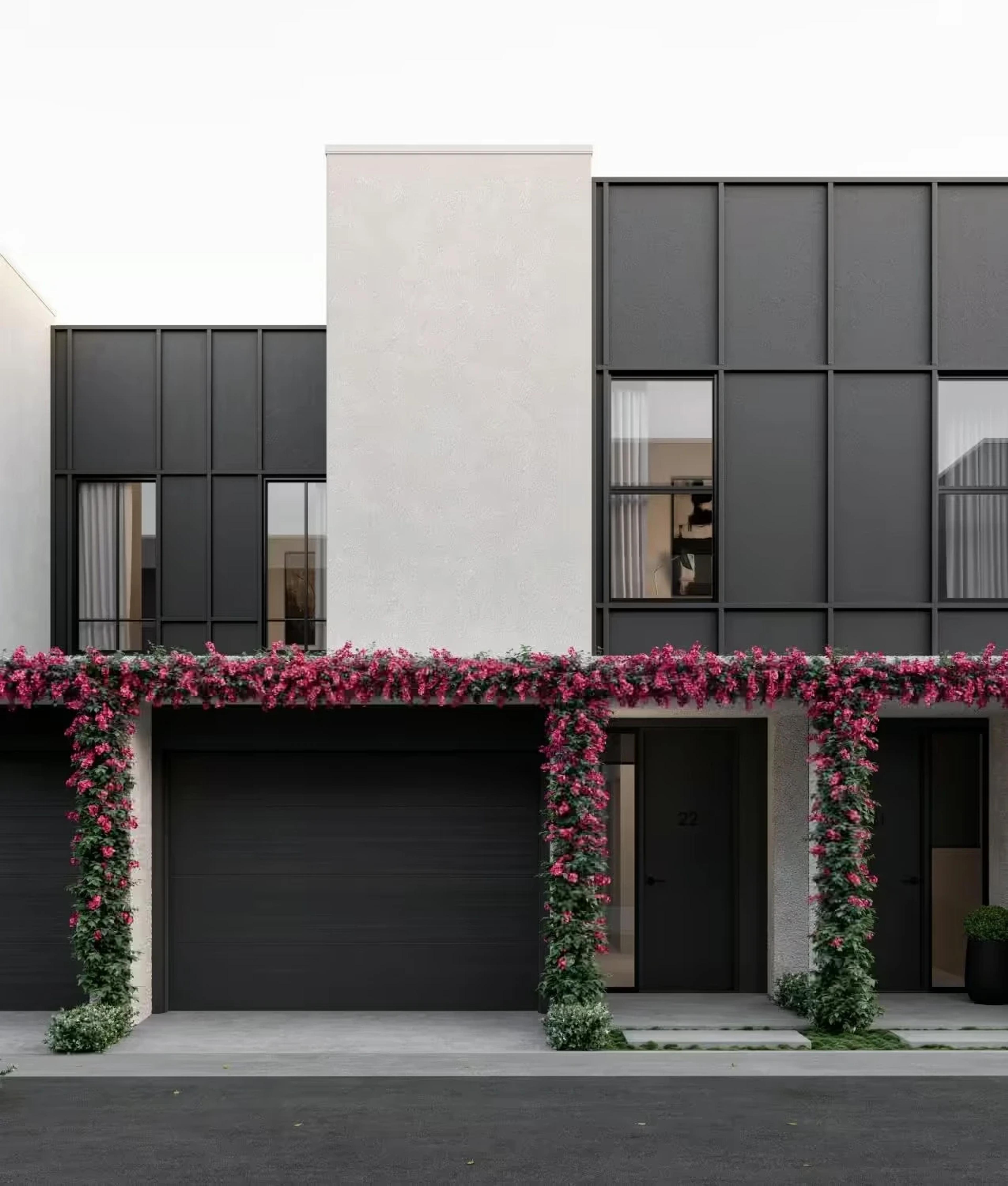 Townhouse facade with black garages and flowering climbing vines