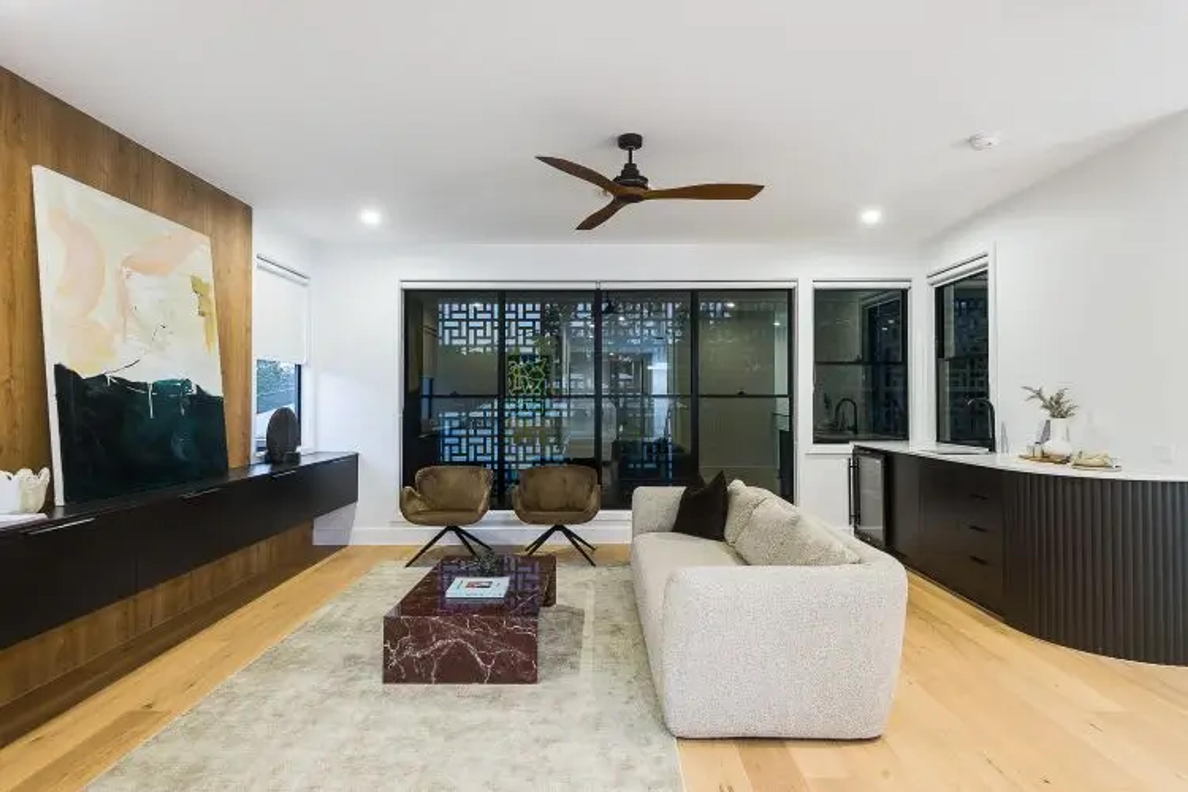 Living area with ceiling fan and sliding doors to courtyard