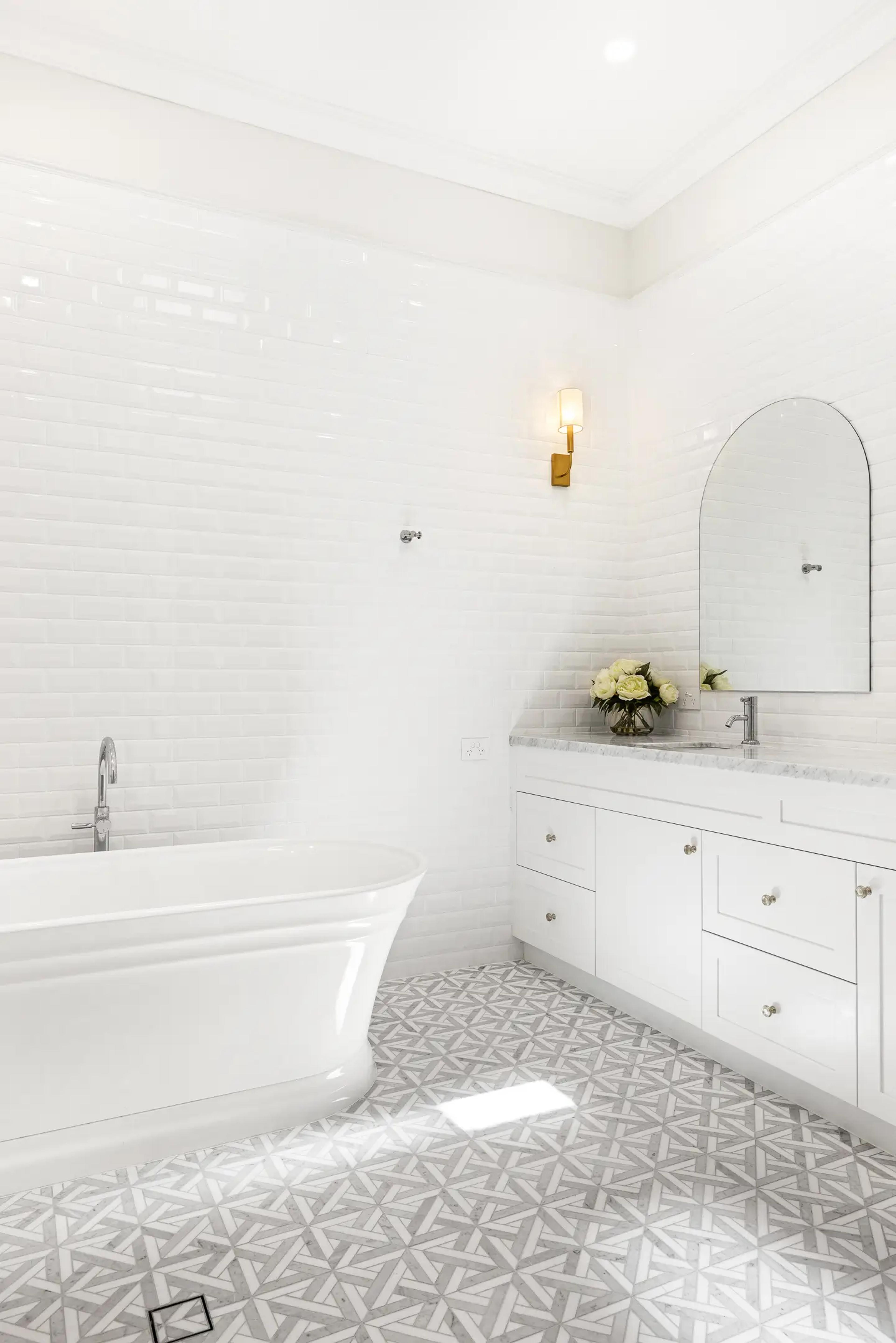 White bathroom with freestanding bath and patterned floor