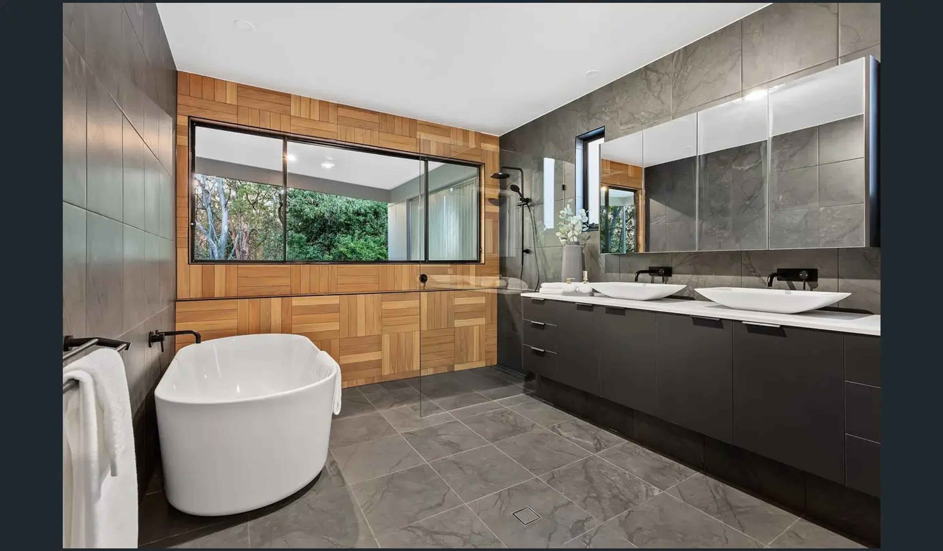 Bathroom with freestanding bath, timber wall and twin basins