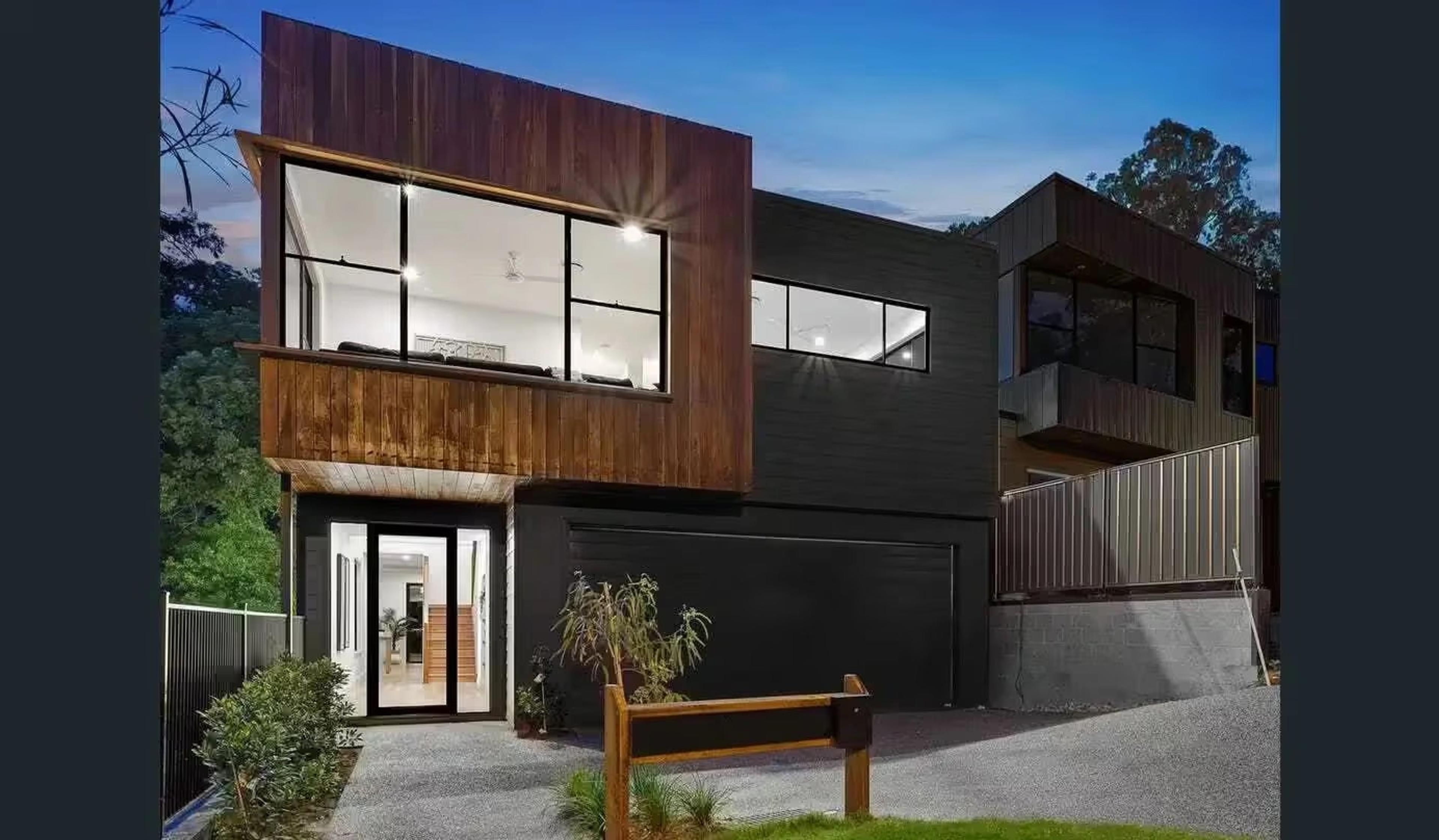 Two storey home facade at dusk with entry, garage and driveway