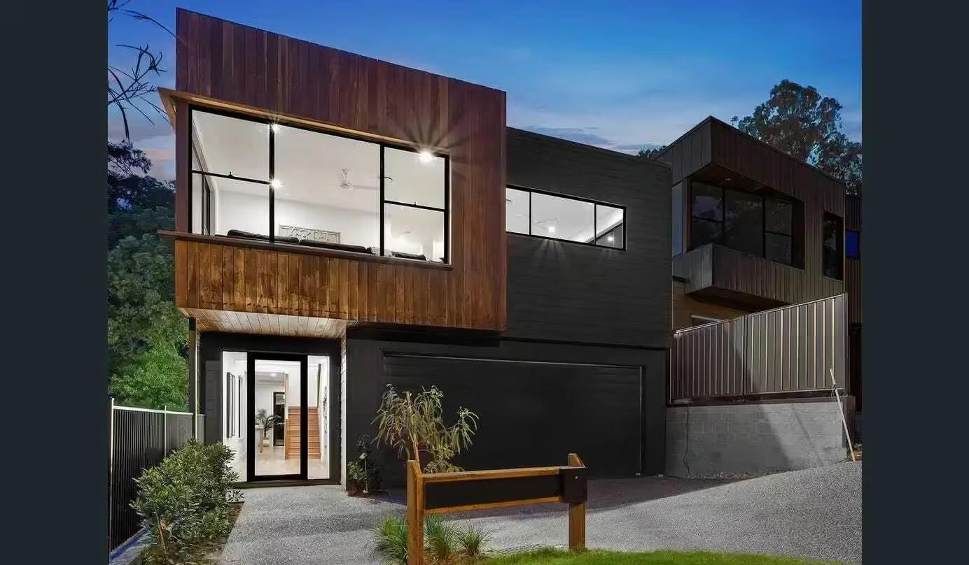 Two storey home facade at dusk with entry, garage and driveway