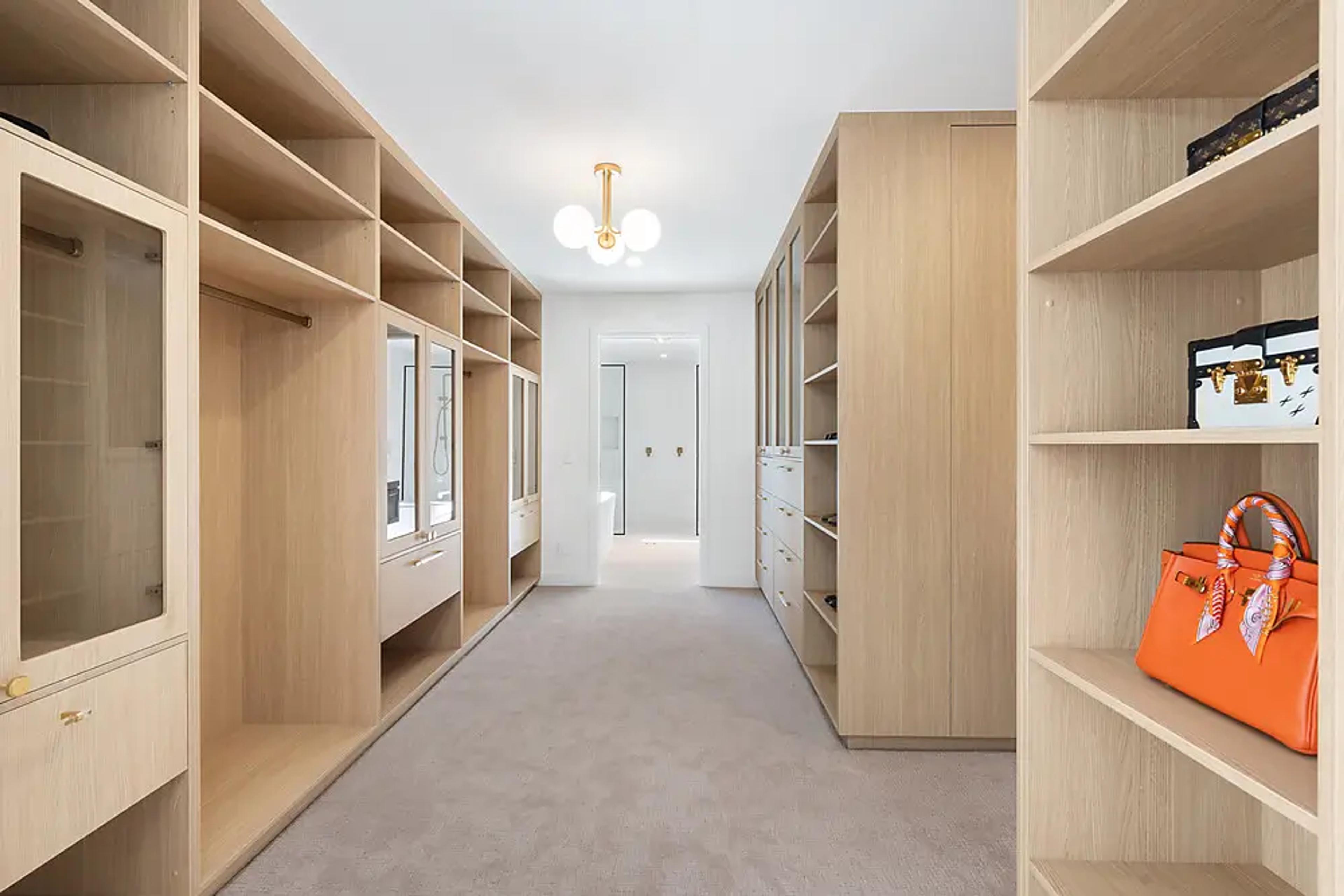 Walk-in wardrobe with timber shelving and carpeted floor.