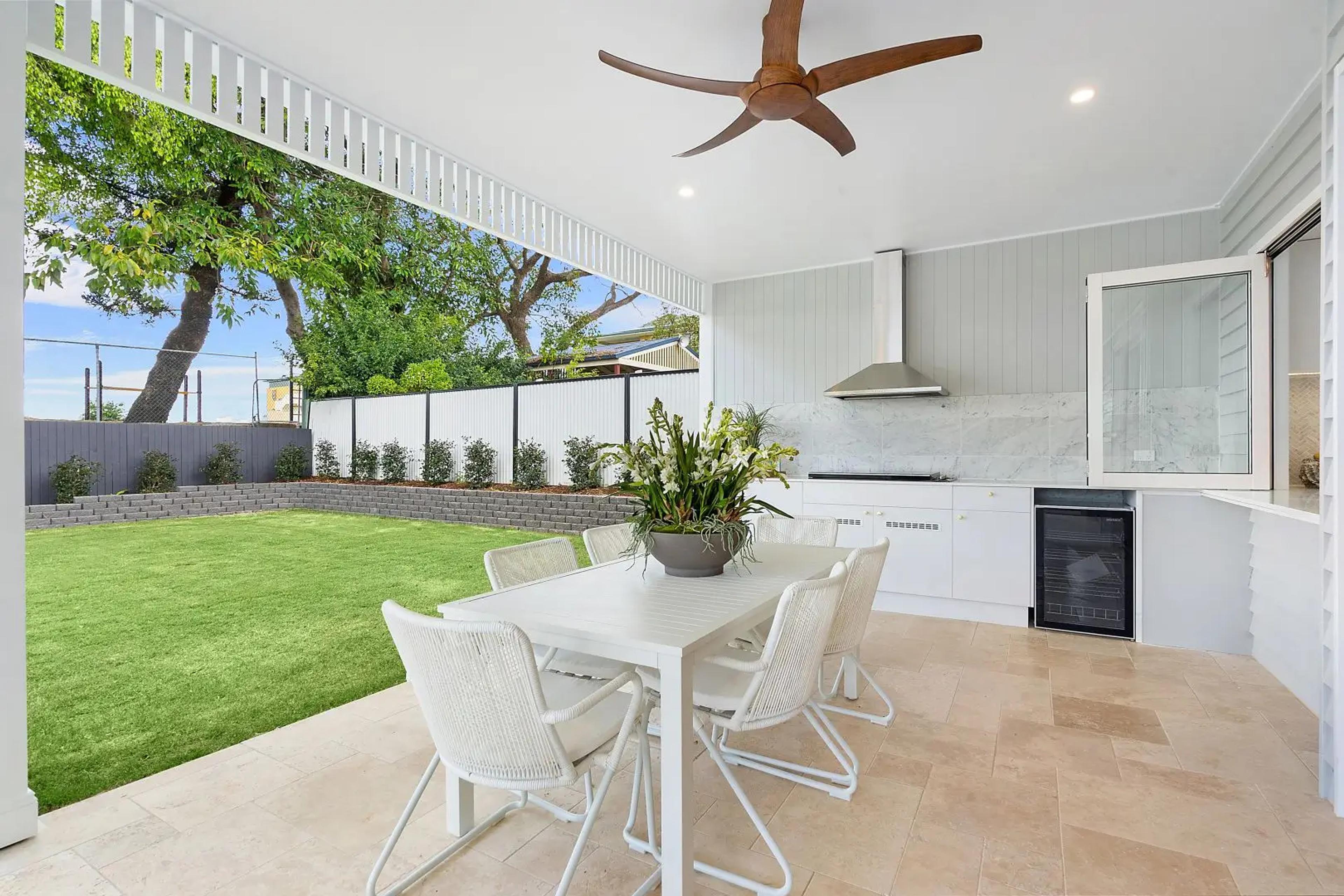 Covered outdoor dining and kitchen beside grassed yard