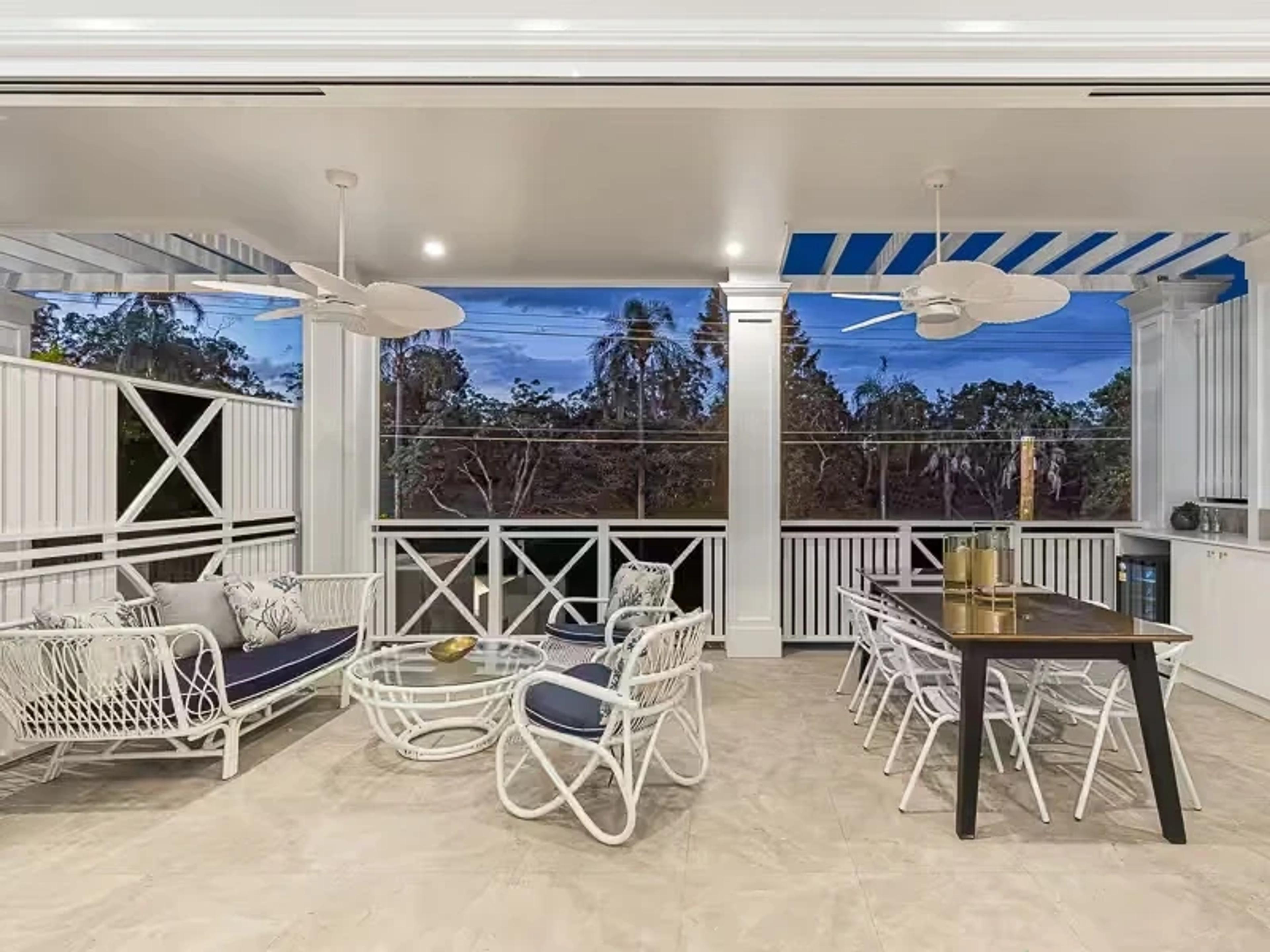 Covered verandah with lounge and dining setting at dusk