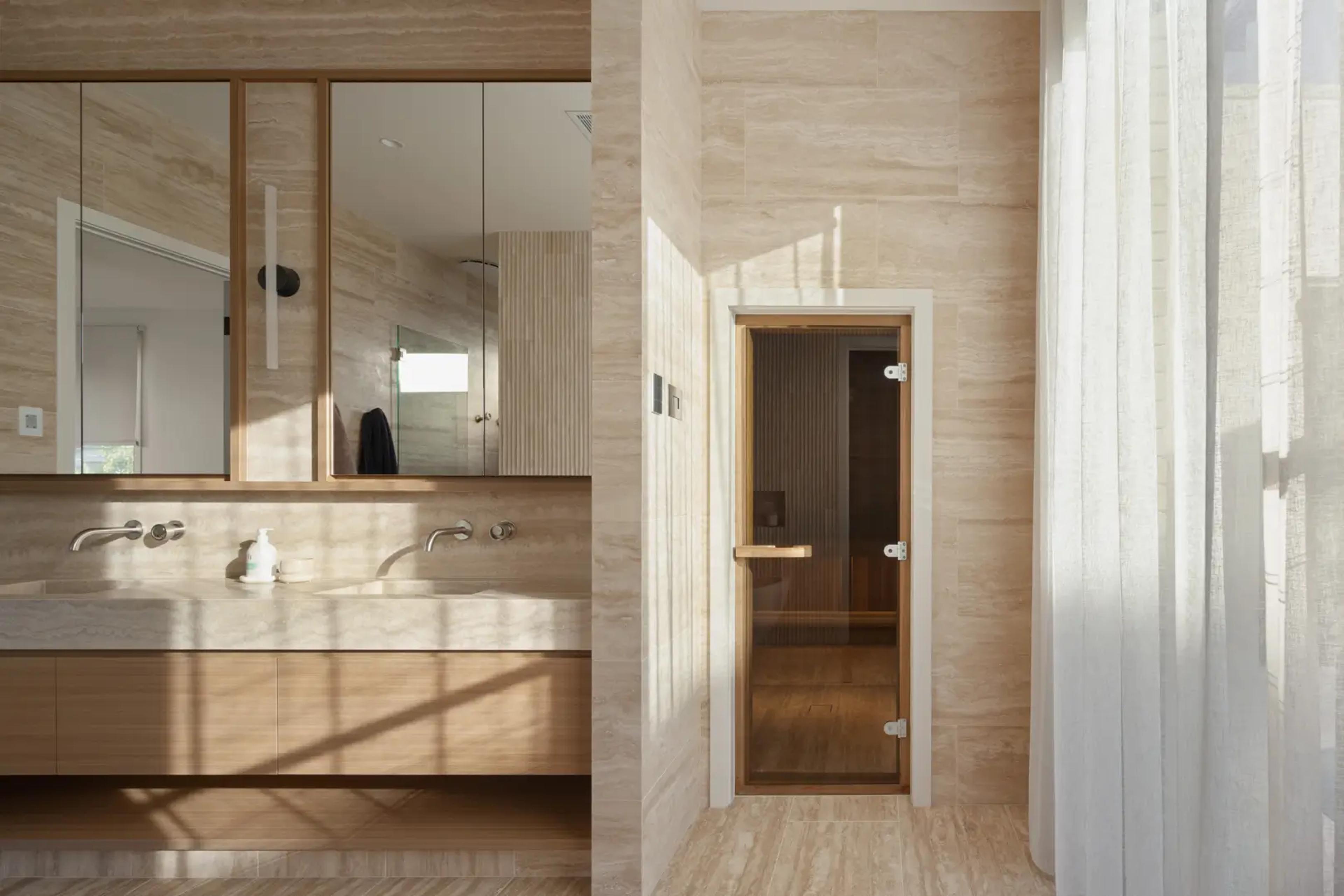 Bathroom vanity beside glass sauna door and sheer curtain