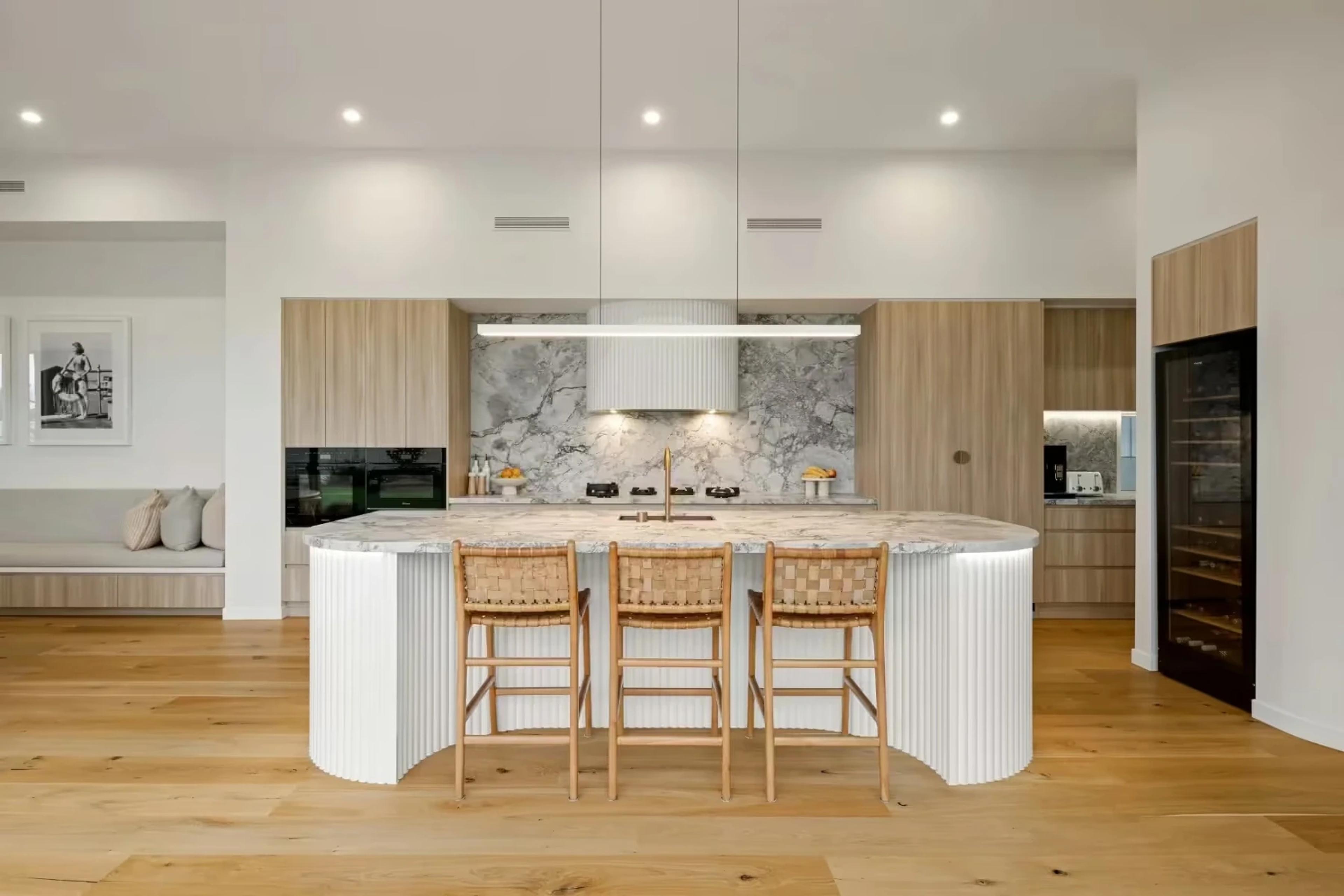 Curved marble island bench with rattan stools and pendant light