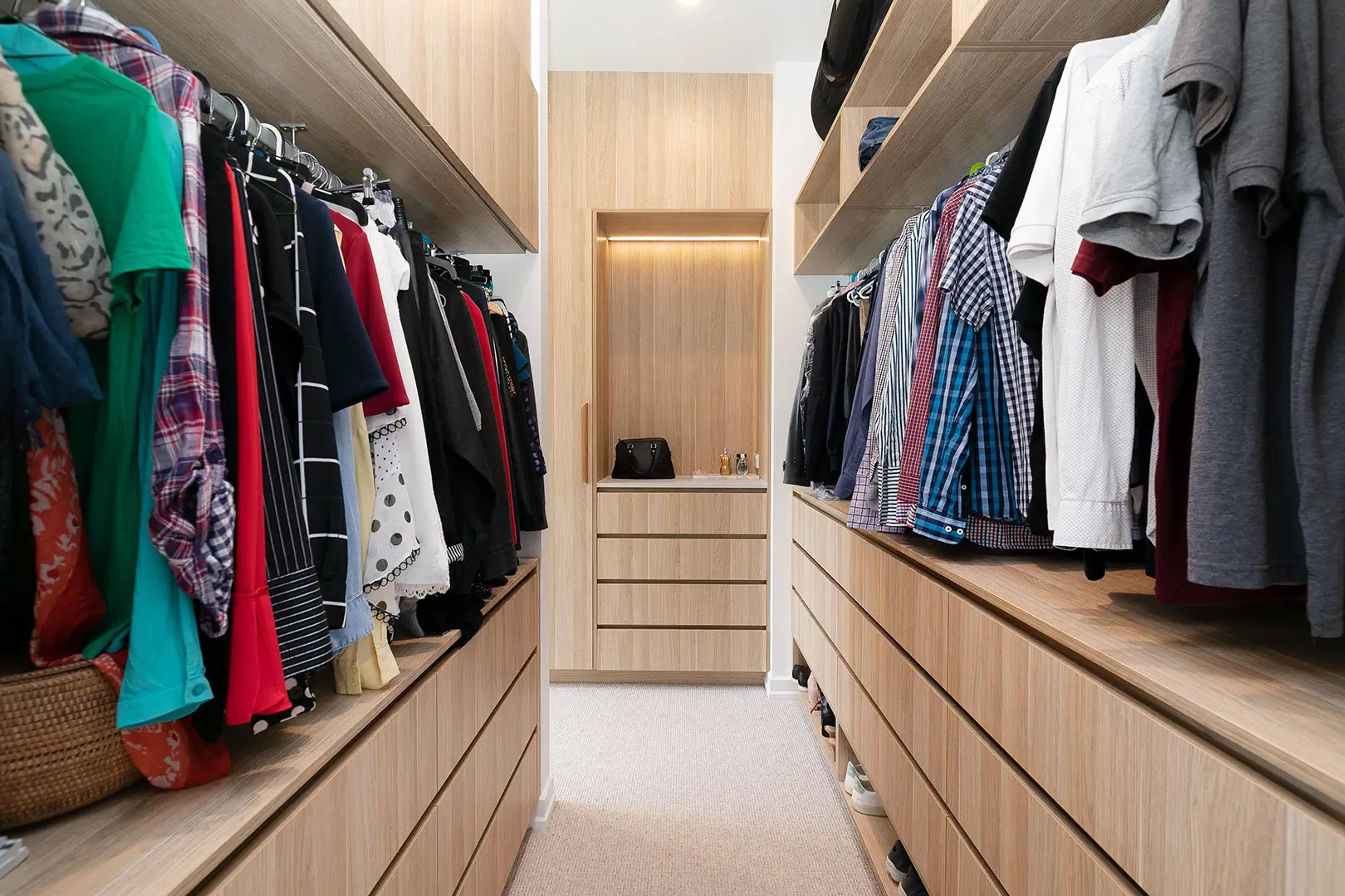 Walk in wardrobe with timber joinery and hanging clothes