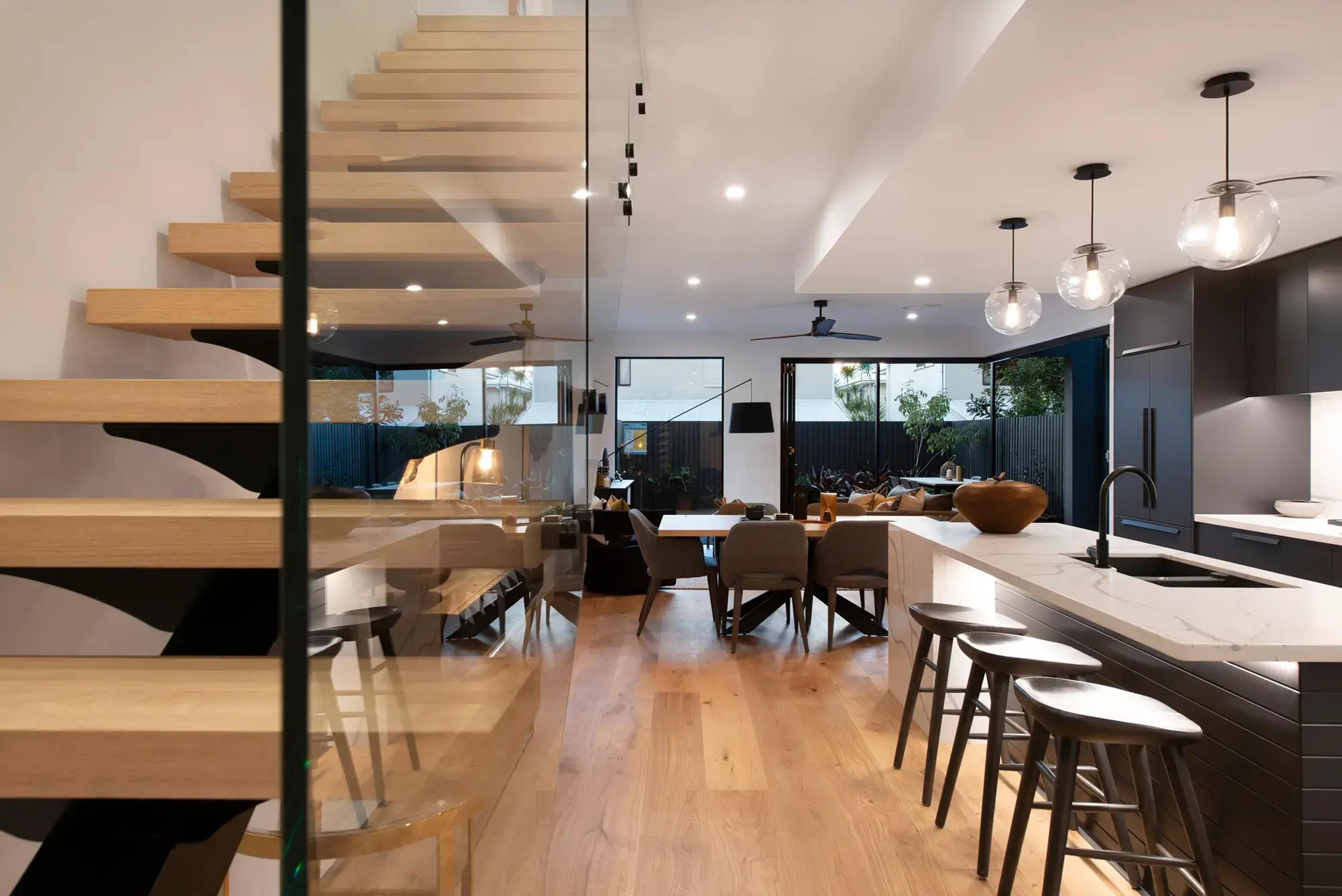 Timber floating staircase beside open plan kitchen and dining