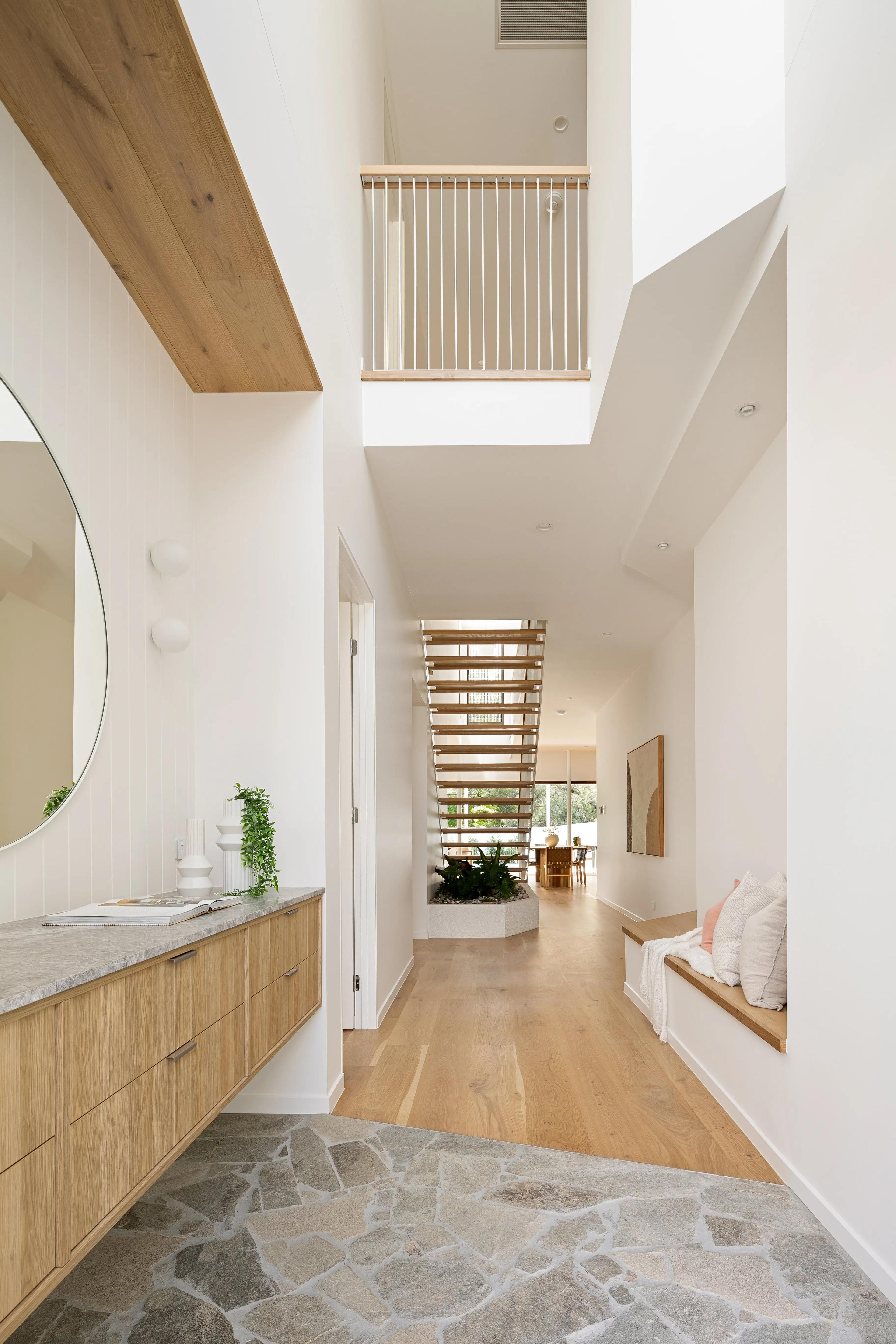 Double height entry hallway with timber stairs and stone floor
