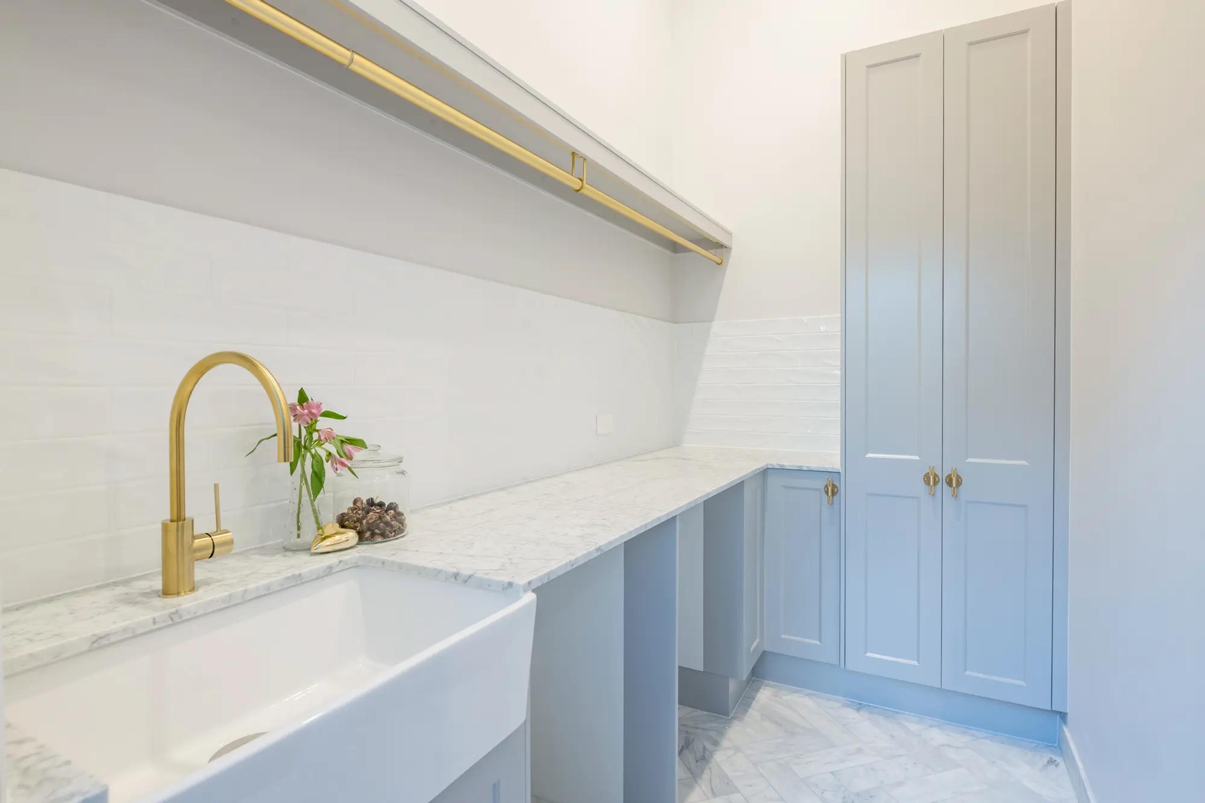 Laundry with blue cabinets and brass sink tap