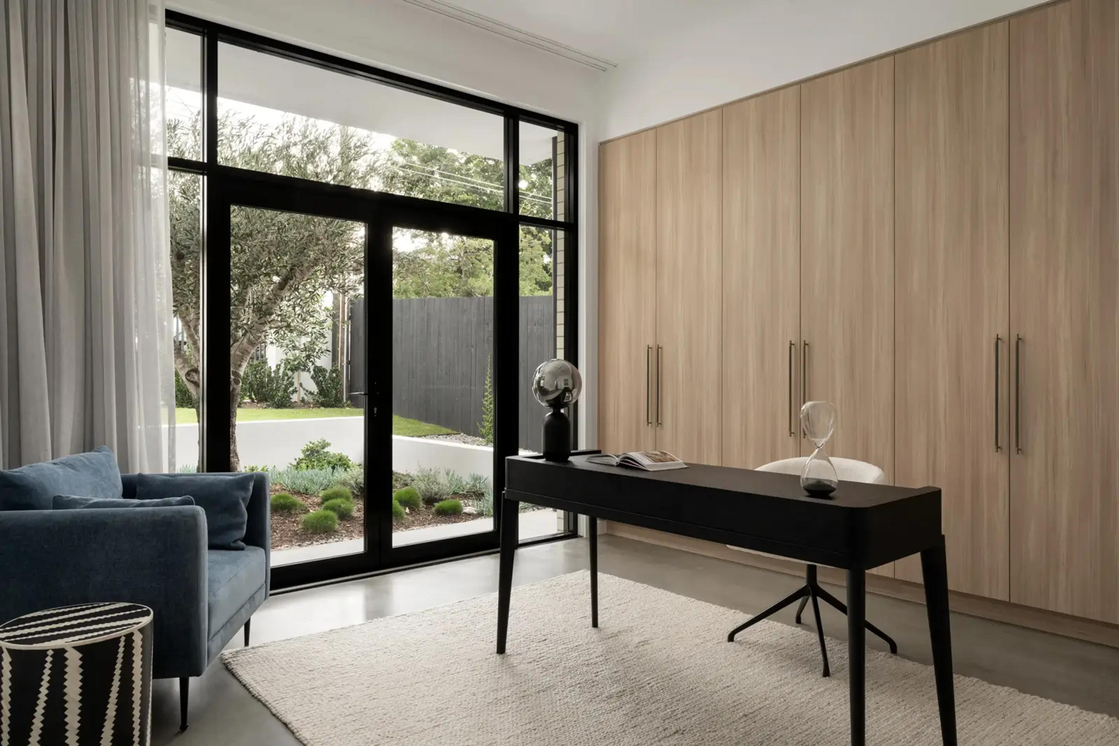 Home office with black desk, timber cabinetry and garden outlook