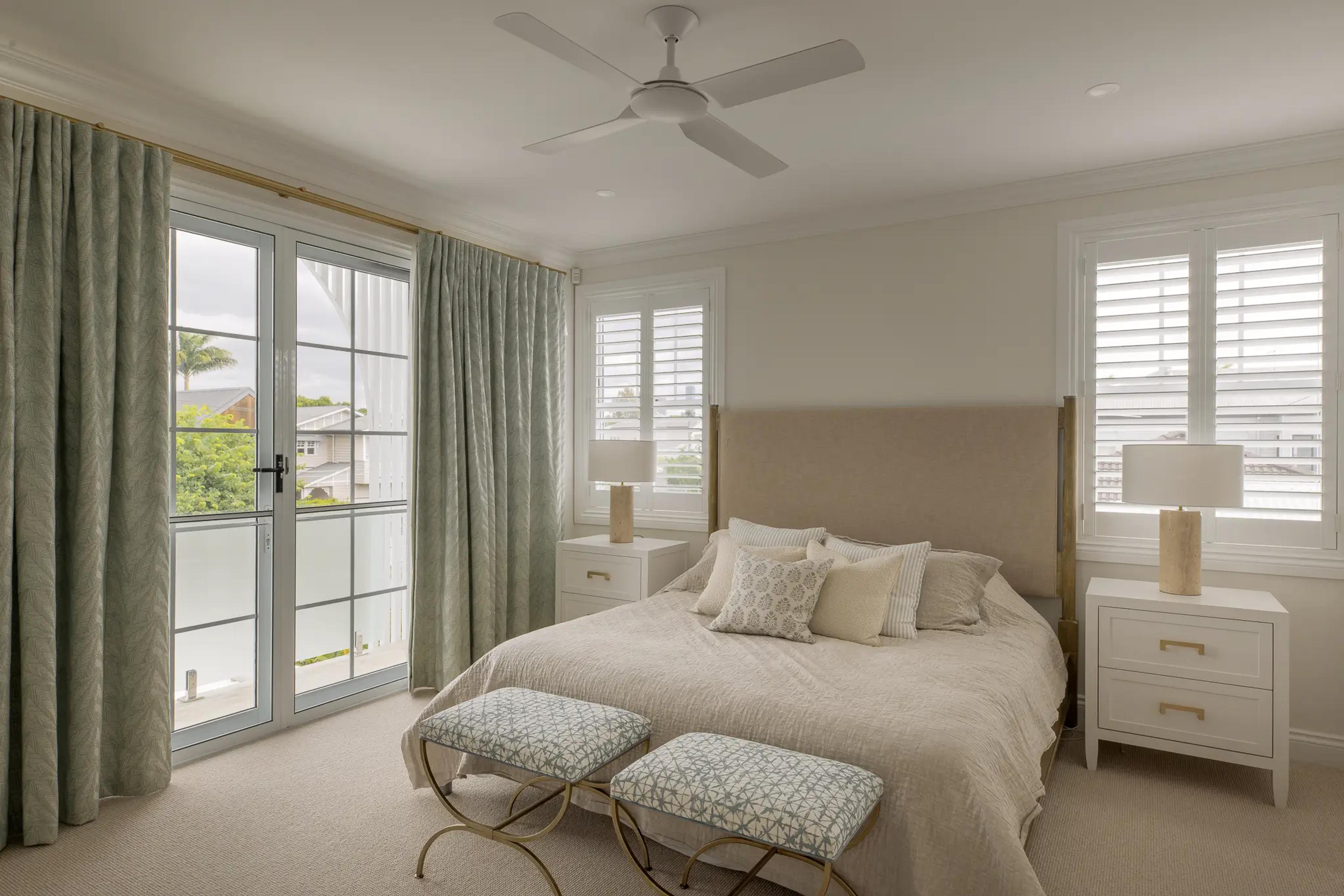 Bedroom with upholstered bed, plantation shutters and French doors