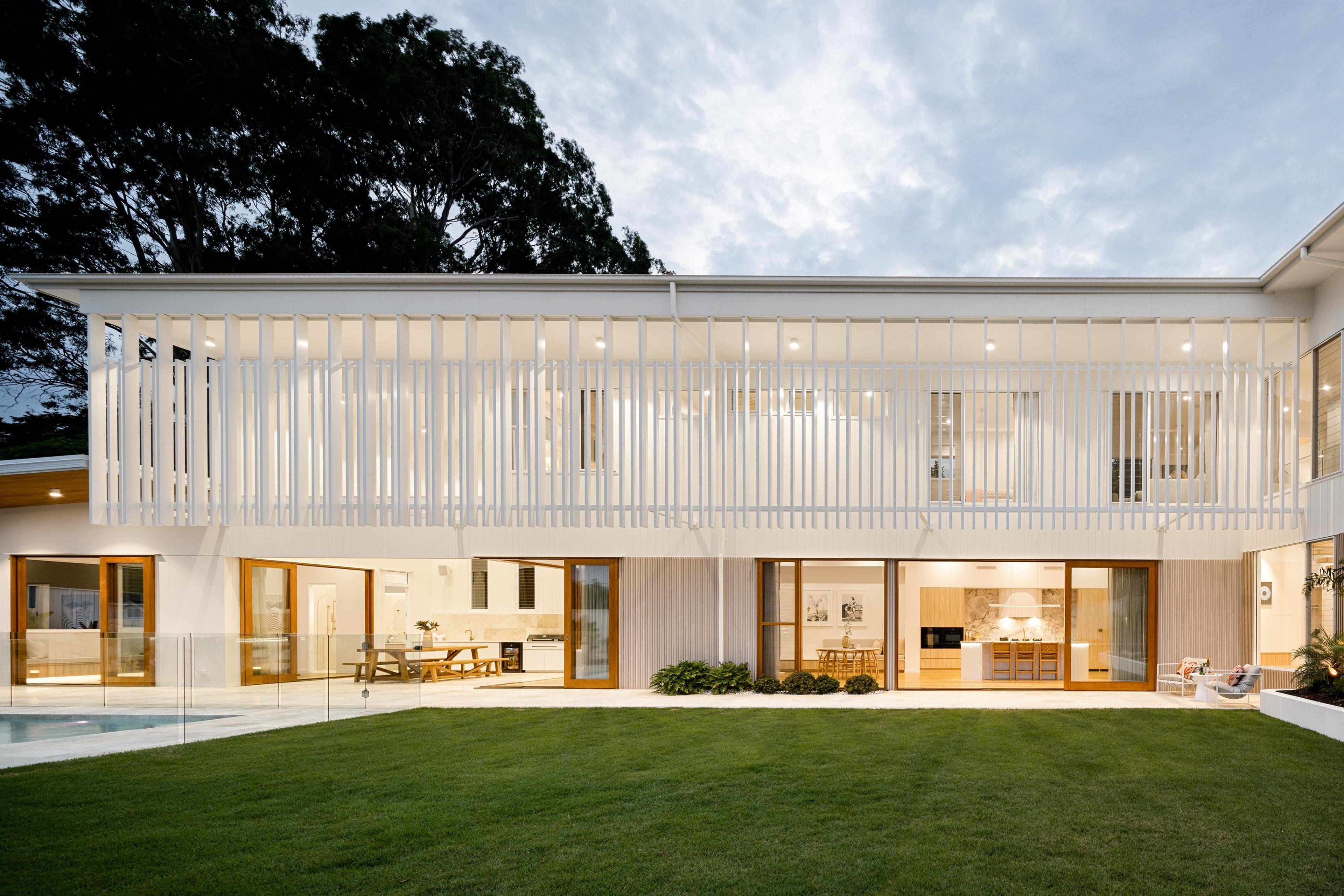 Rear elevation of white home with battened upper level and glass doors