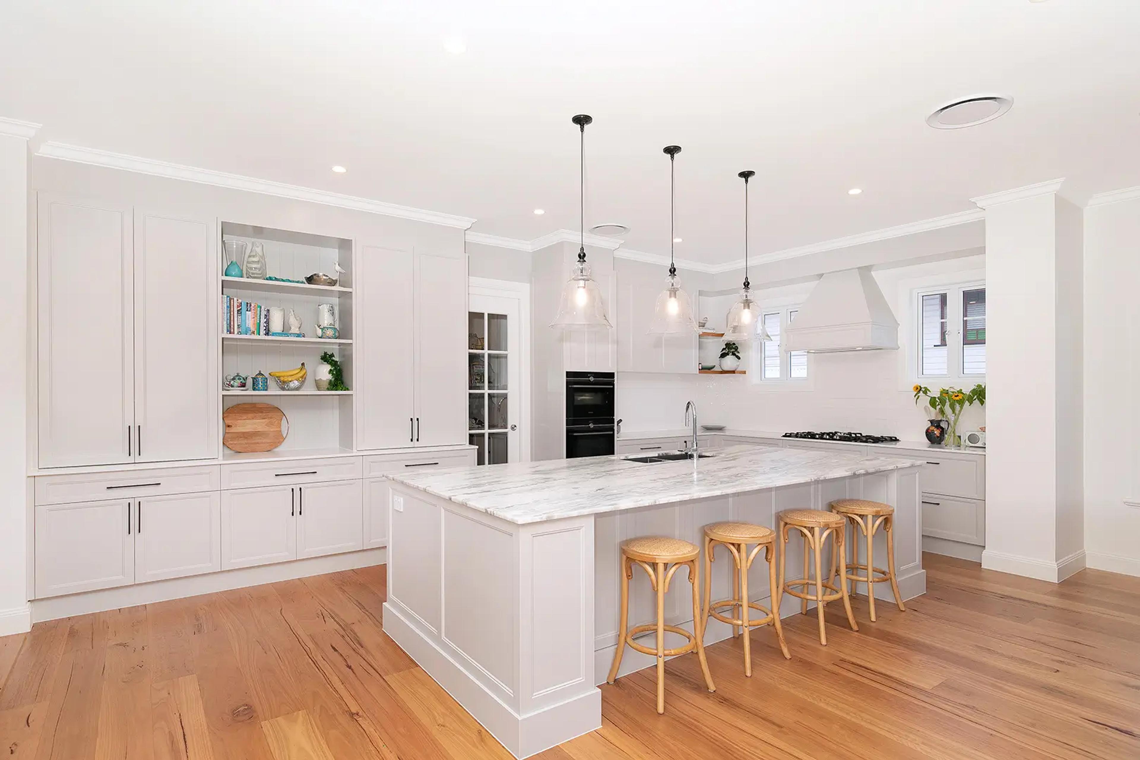 White kitchen with marble island and pendant lights