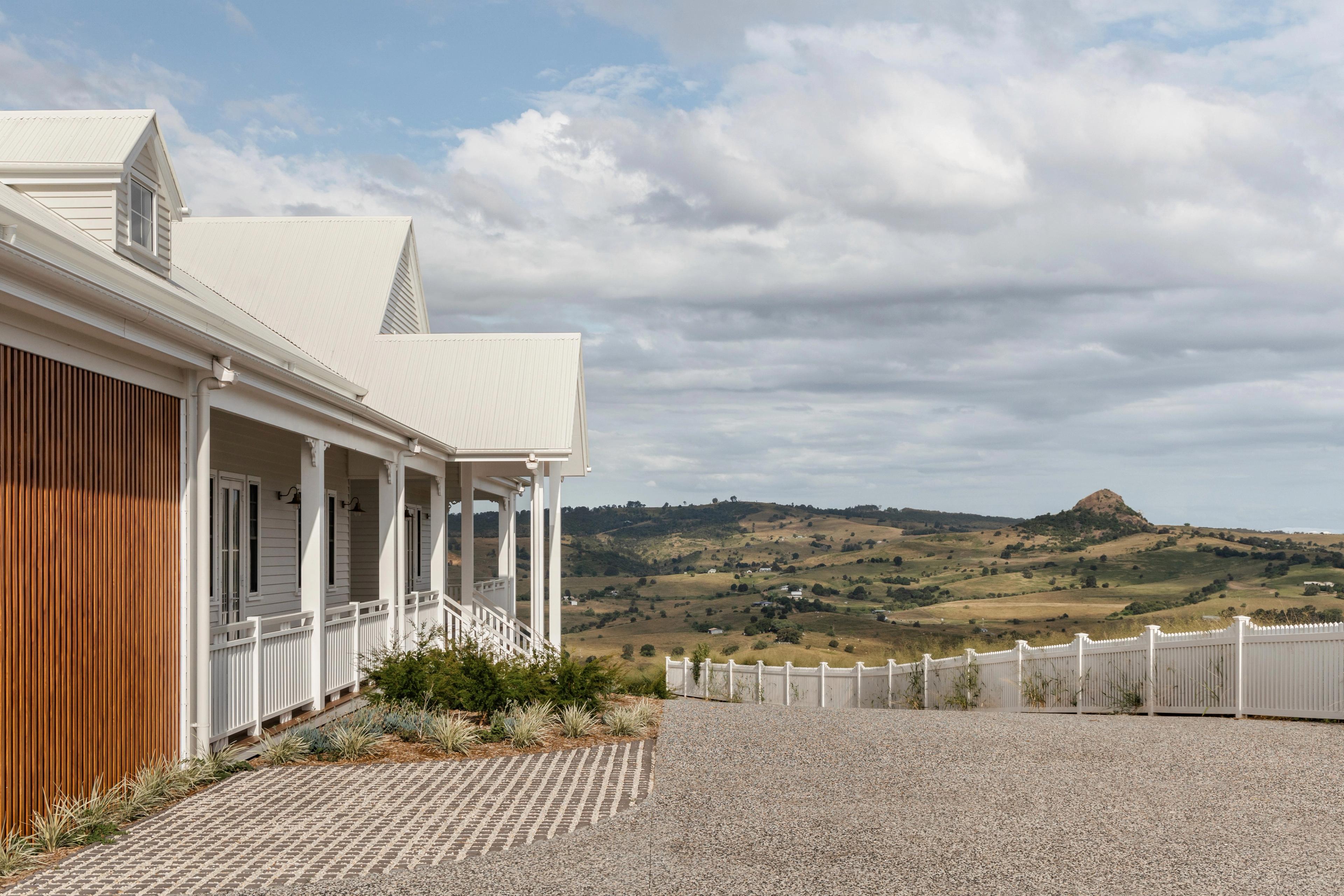 Weatherboard home and verandah overlooking valley and rocky peak