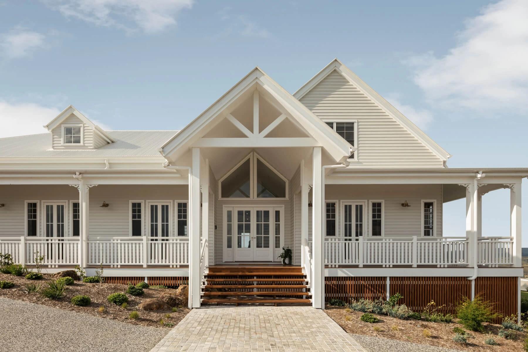 Front entrance of white weatherboard homestead with gabled portico and verandah