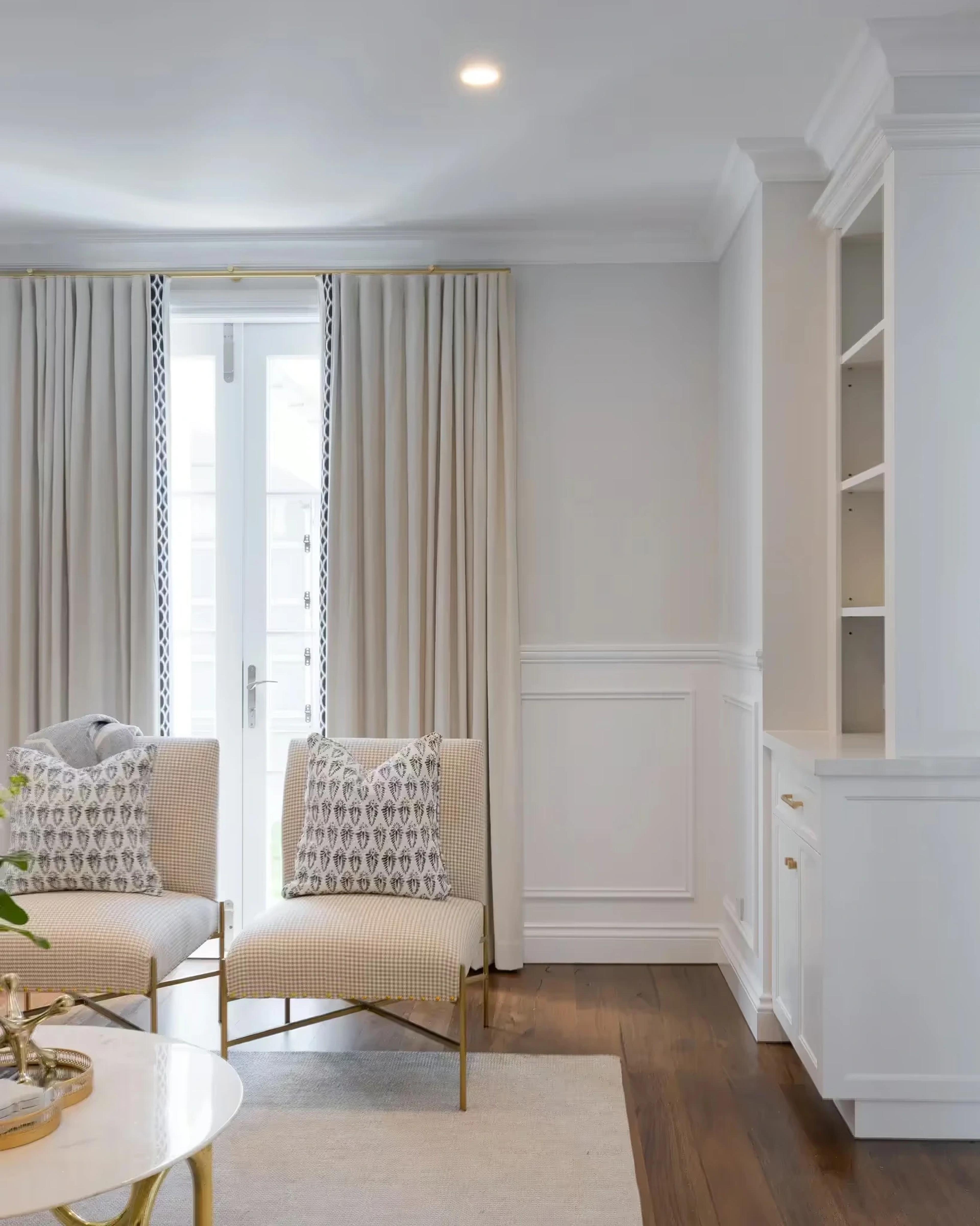 Sitting area with beige armchairs and full length curtains