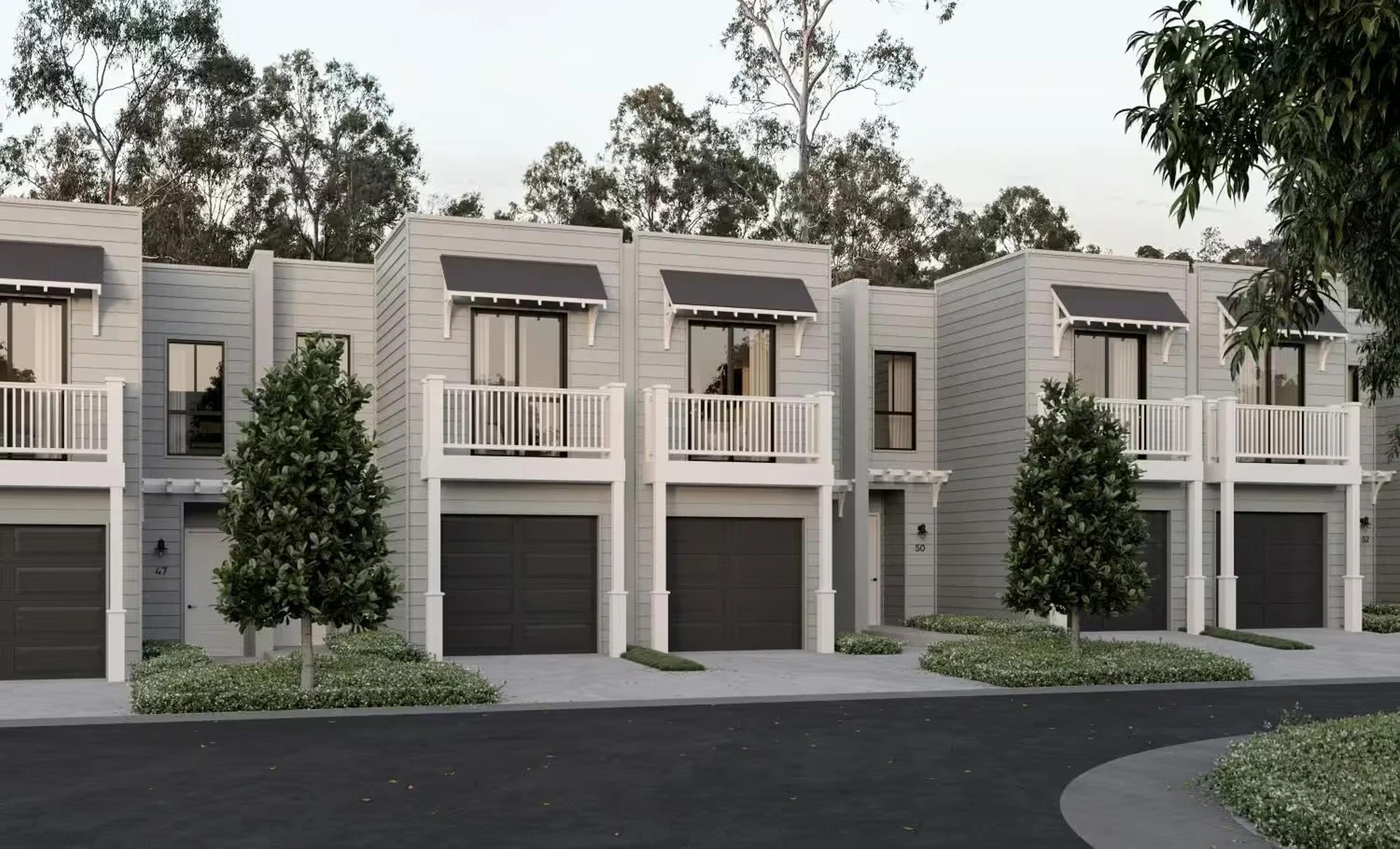 Angled row of white townhouses with balconies and garages