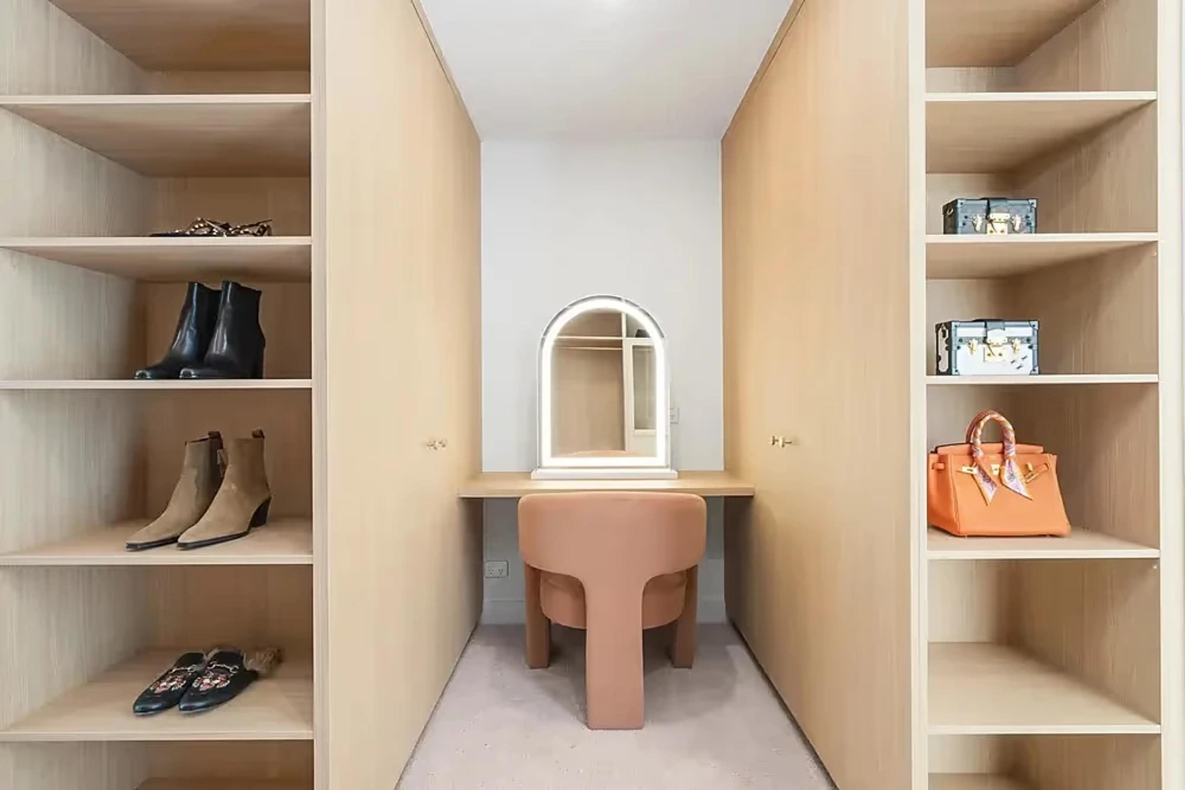 Dressing area with timber cabinetry, vanity and arched mirror.
