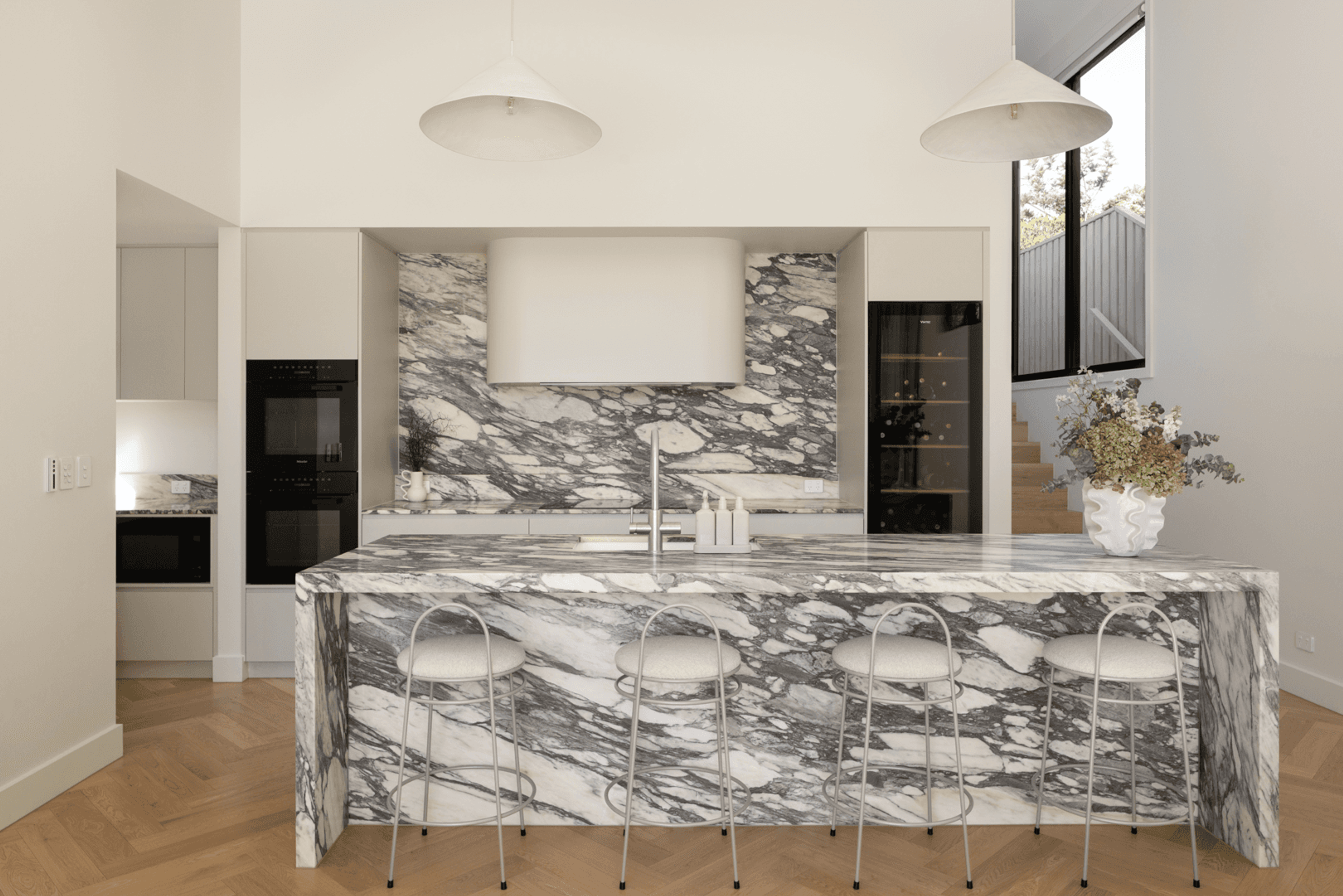 Kitchen marble island with stools and veined splashback