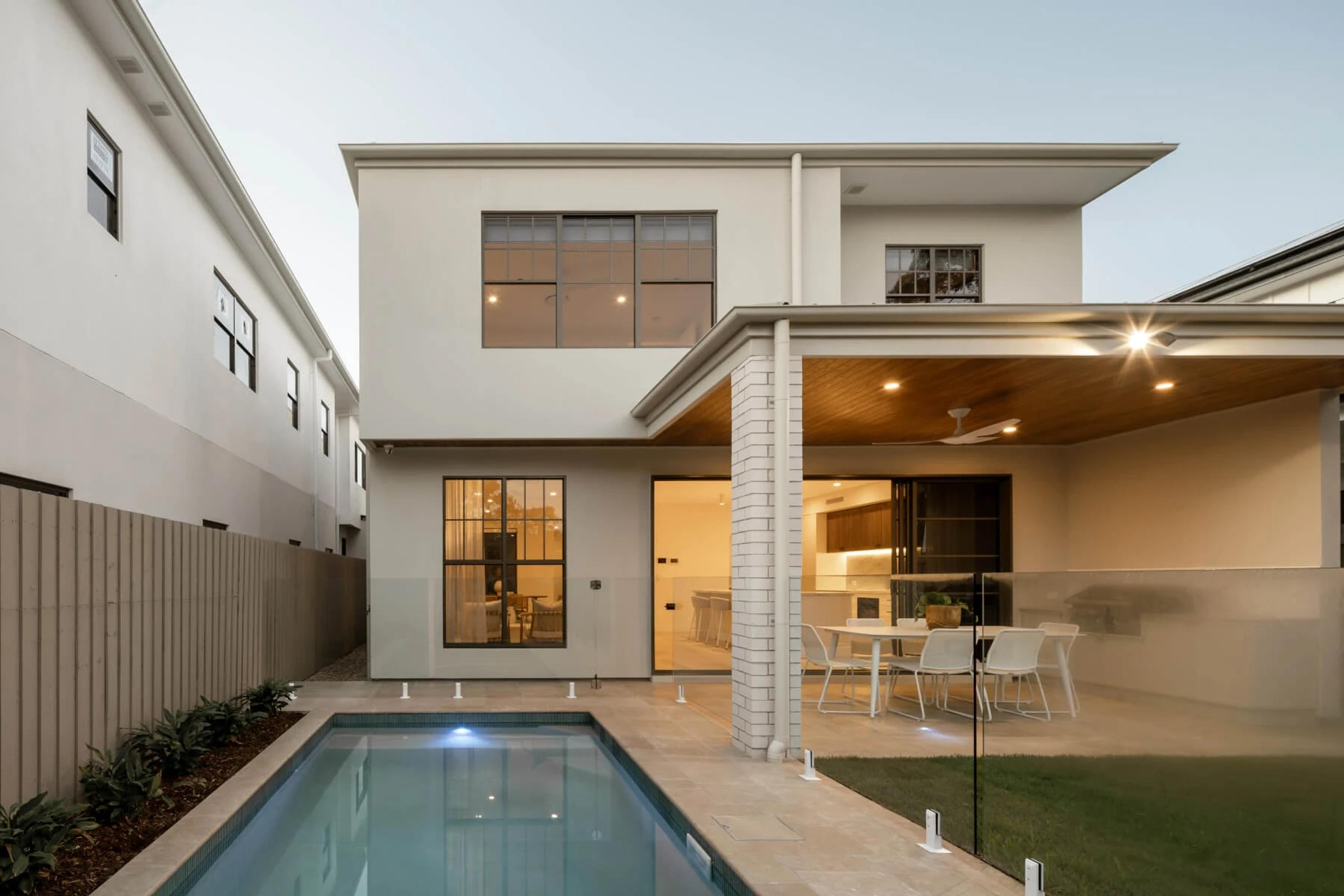 Dusk view of rear facade with pool and covered alfresco