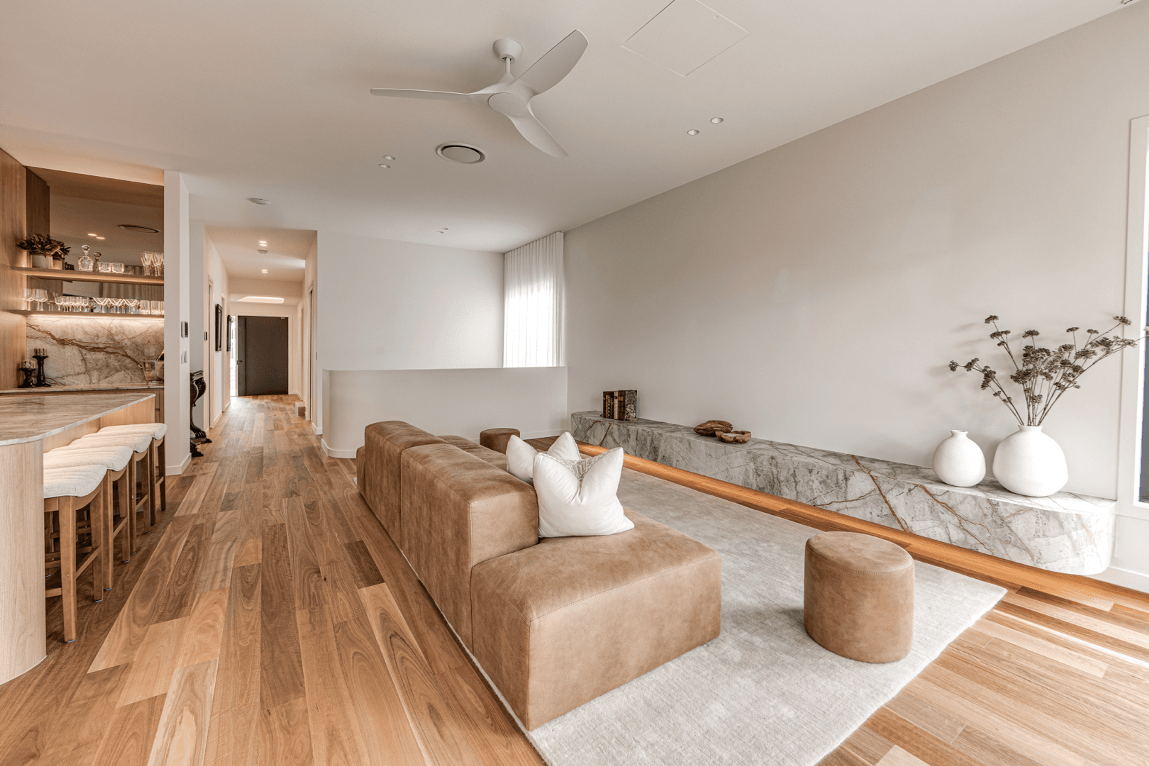 Living room with leather sofa and stone bench beside kitchen