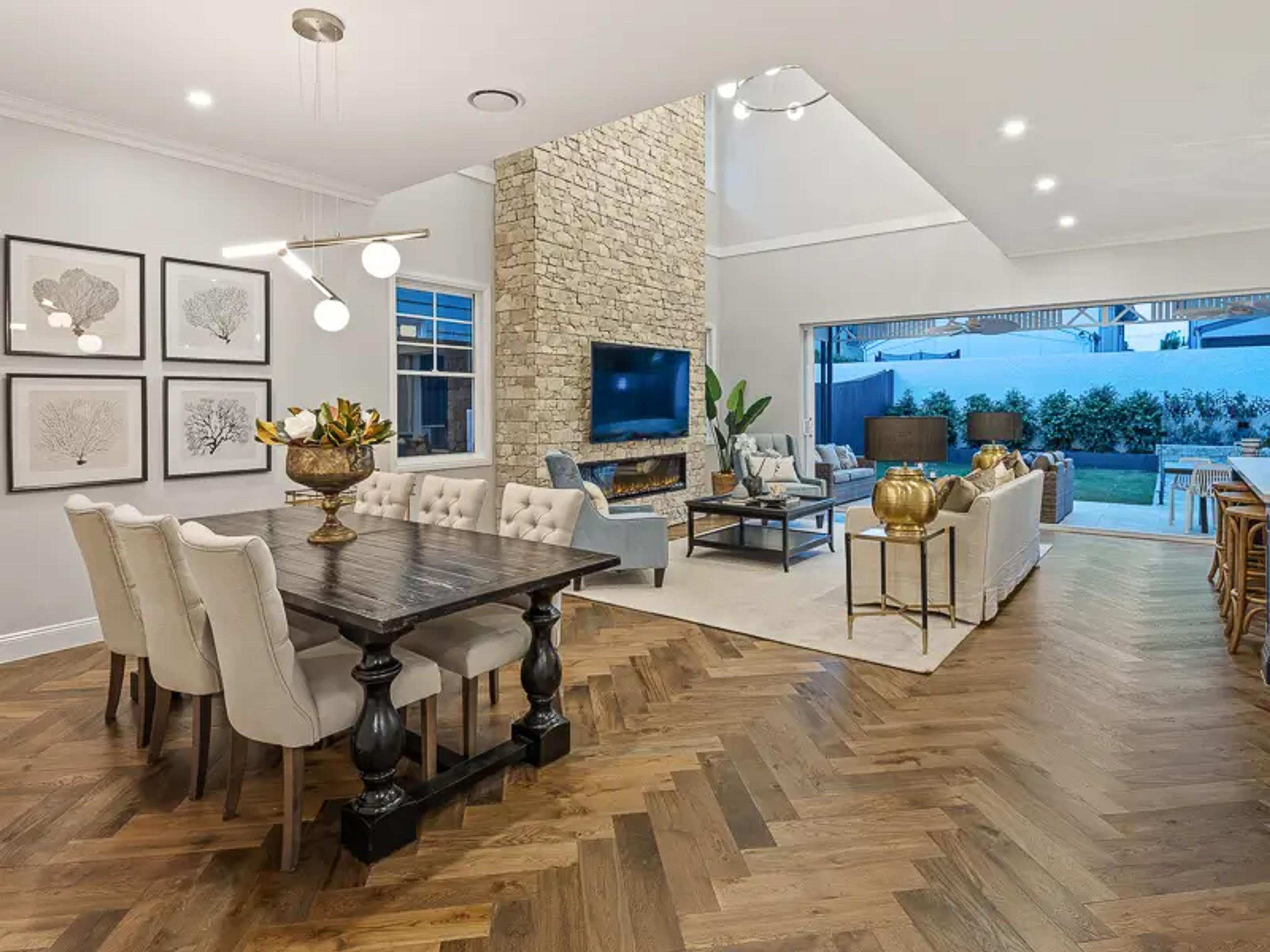 Dining and living room with stone fireplace and herringbone floor