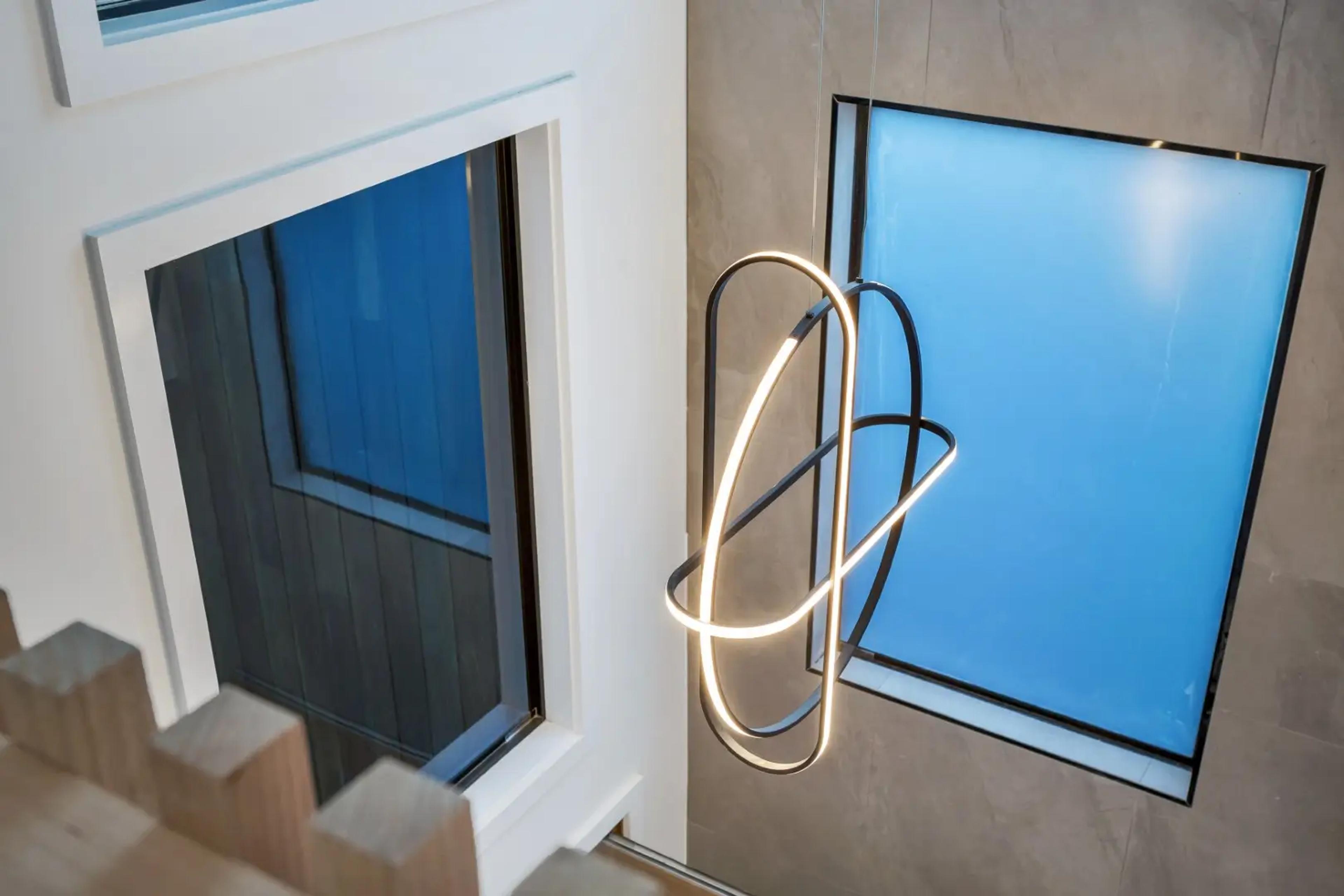 Ring pendant light in stairwell void beside tall windows