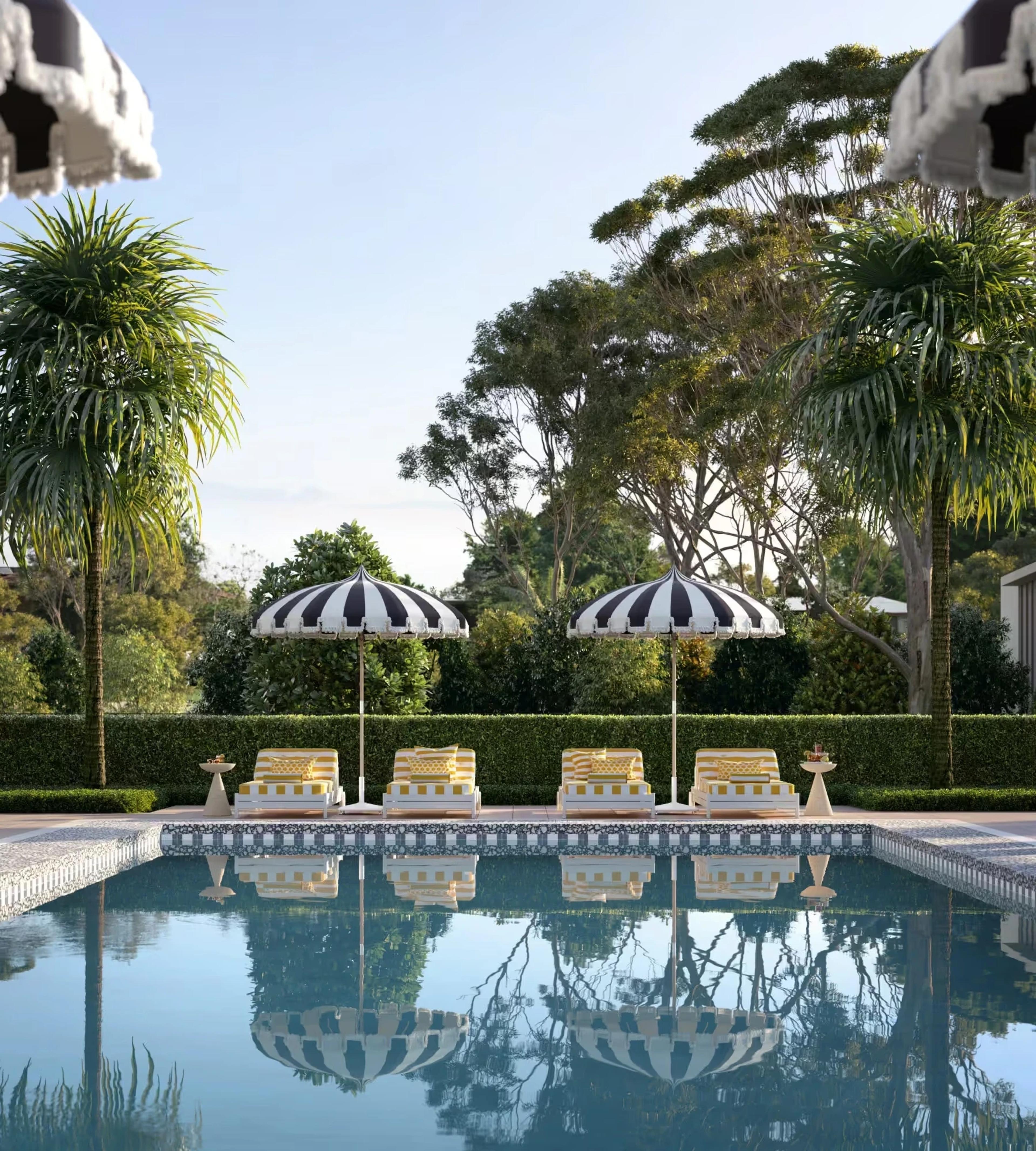 Poolside lounge chairs under black and white striped umbrellas