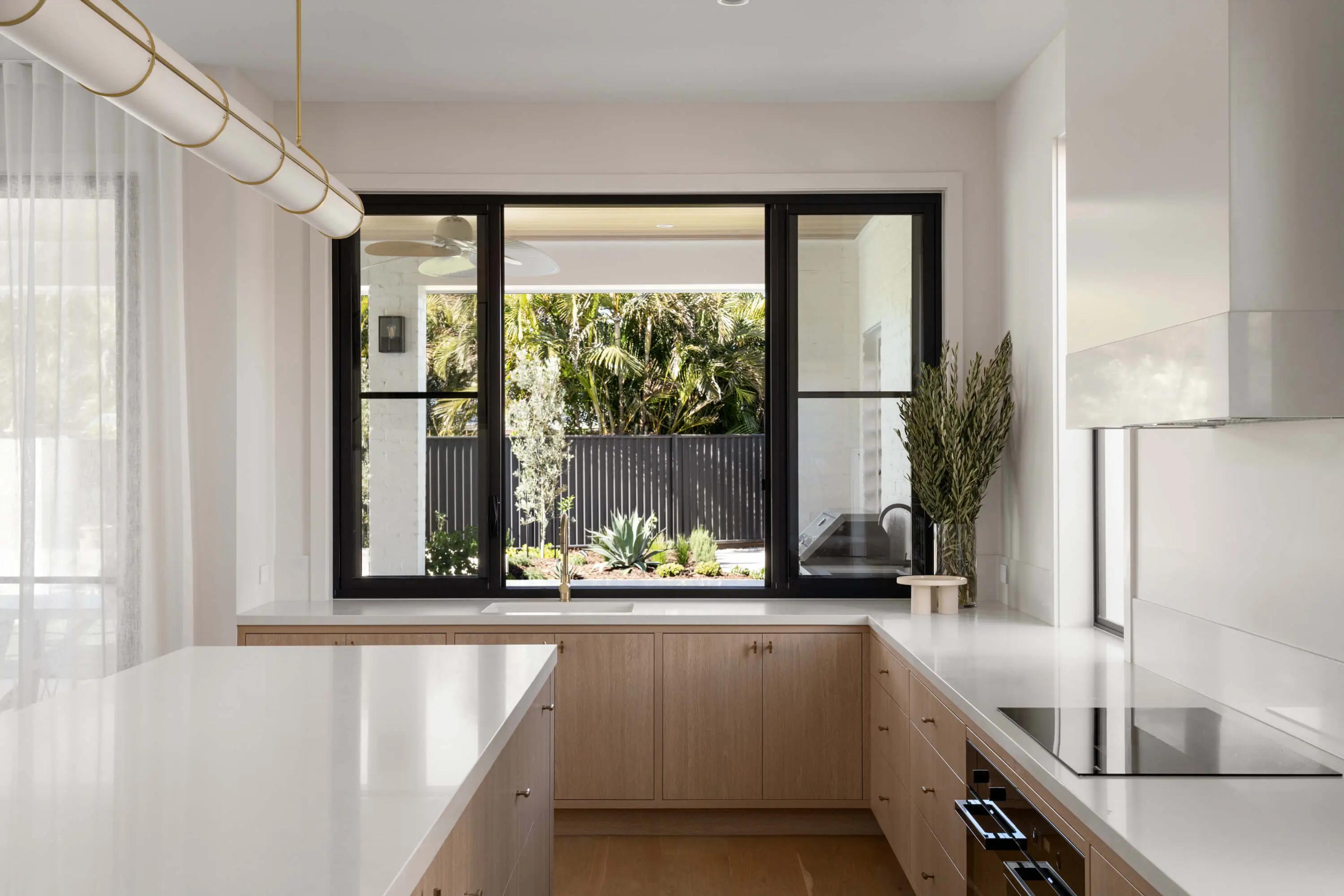 Kitchen with timber cabinetry and black framed windows over sink