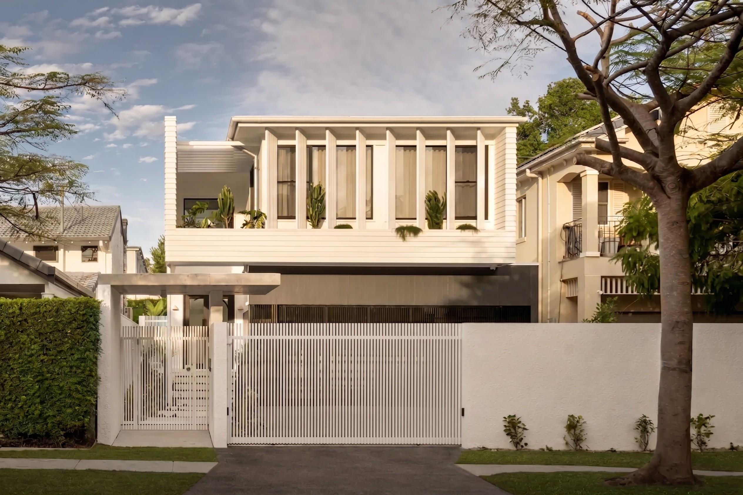 Street view of two storey white home behind front gate