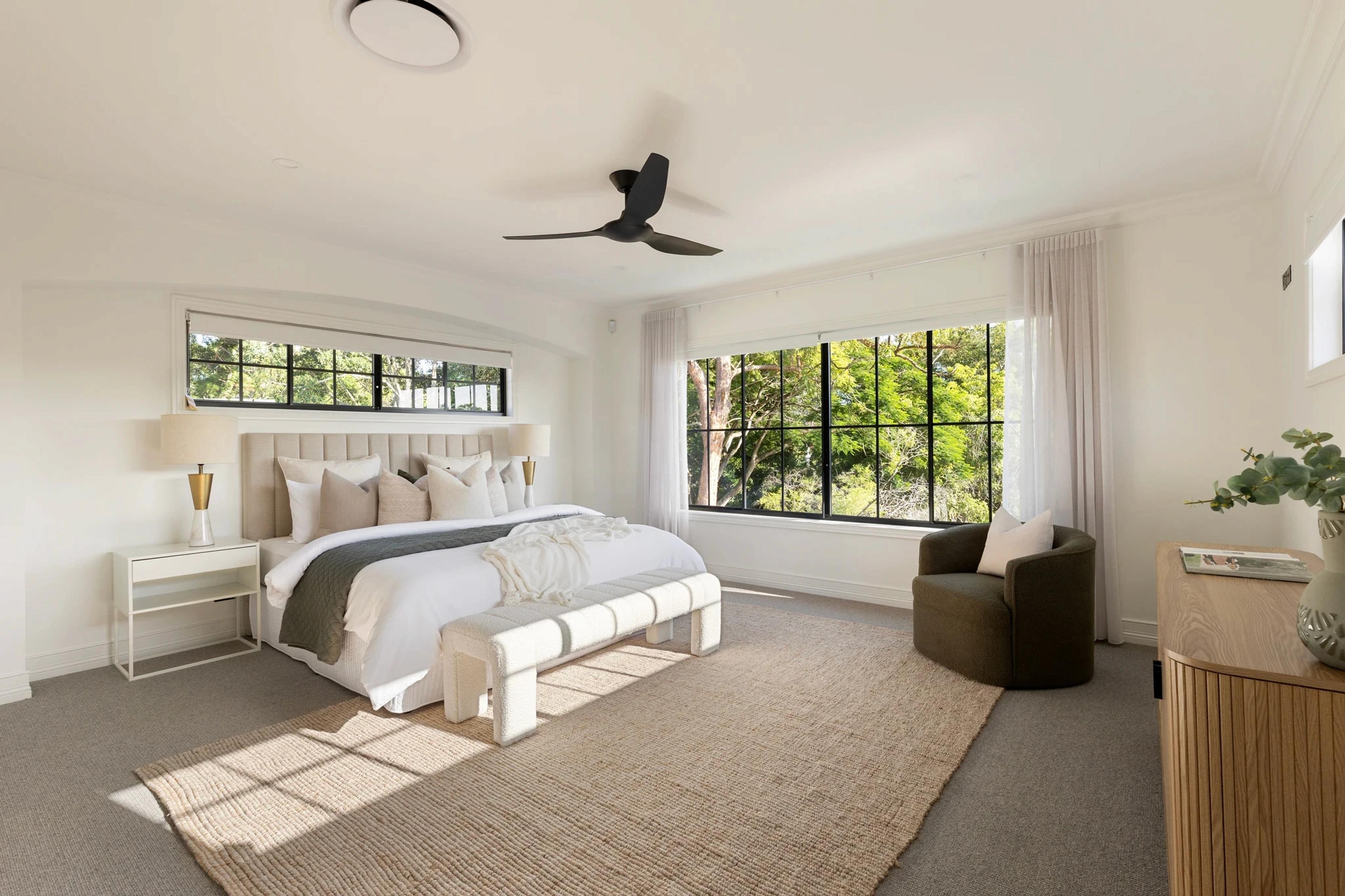 Bedroom with upholstered bed, large windows and leafy outlook