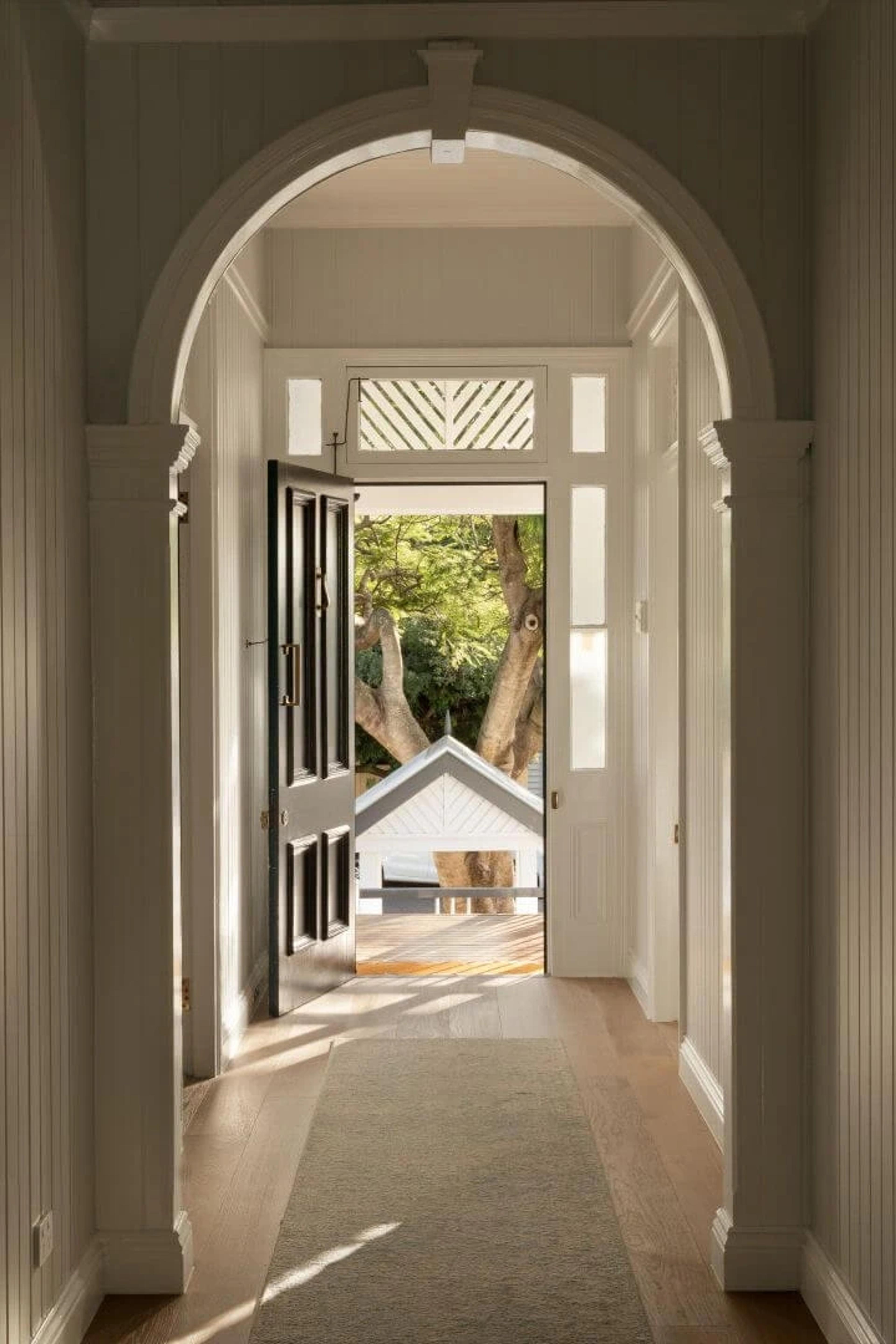Arched hallway with dark front door open to garden view