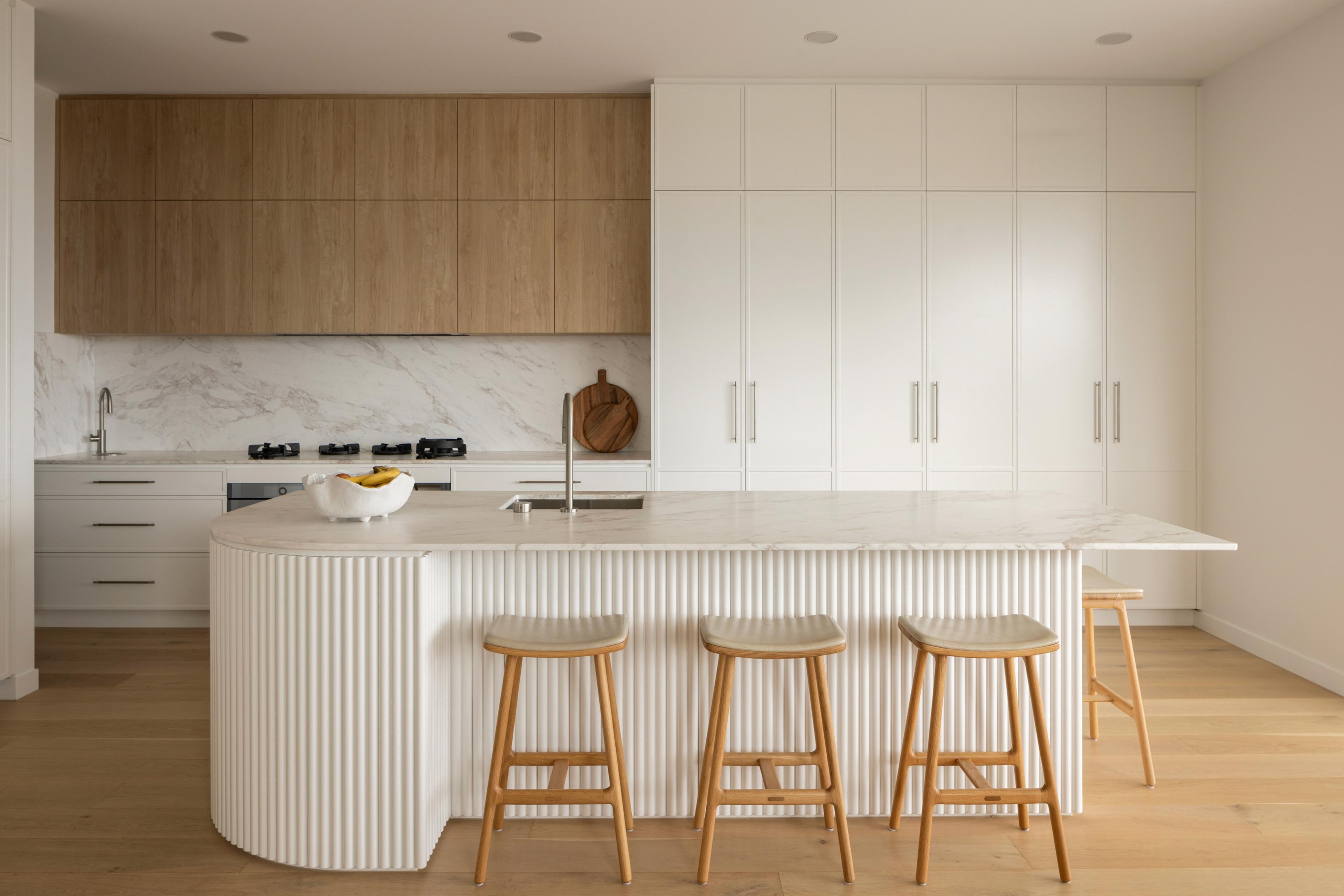 White kitchen with fluted island and timber cabinetry