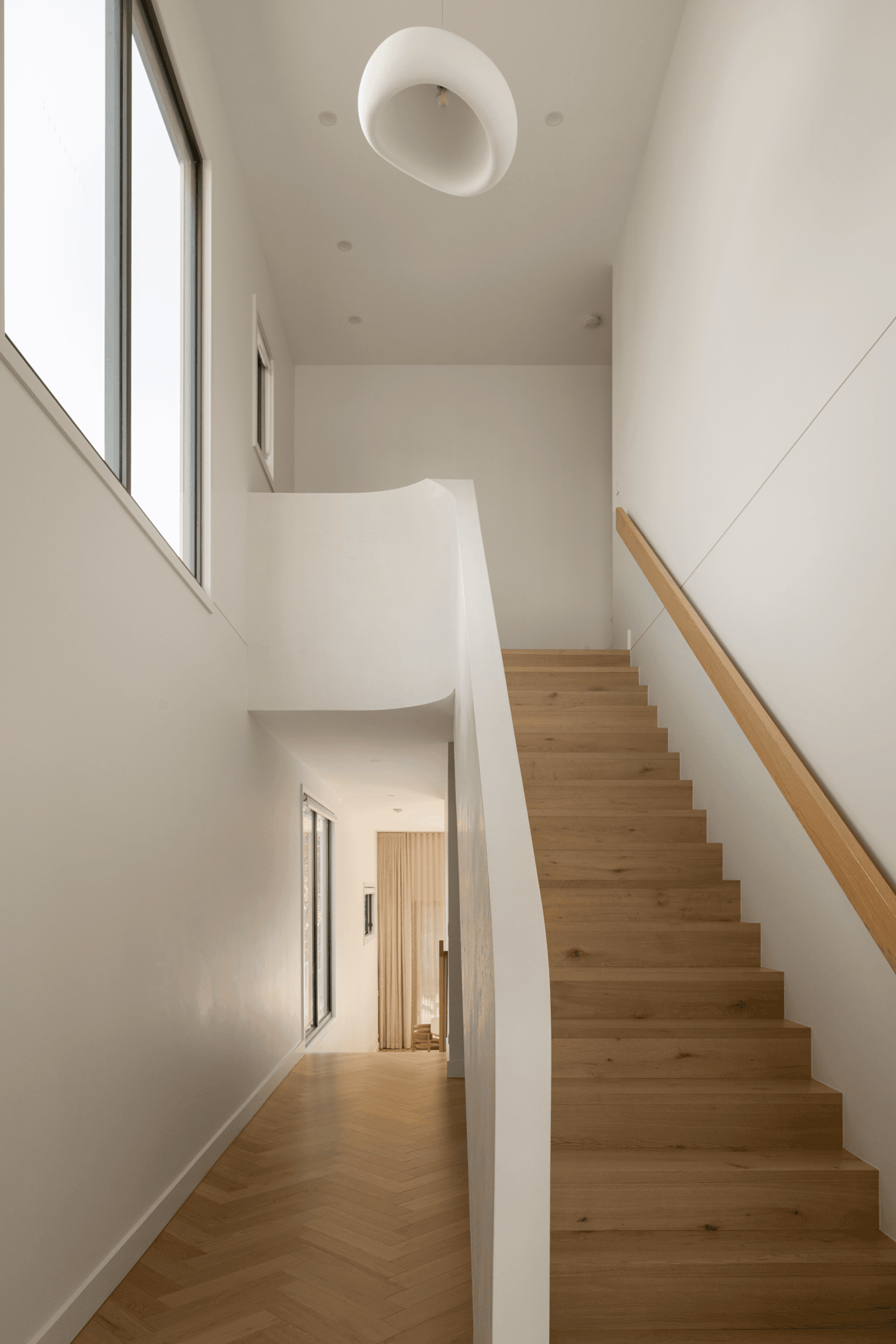 Timber staircase with white balustrade and tall window