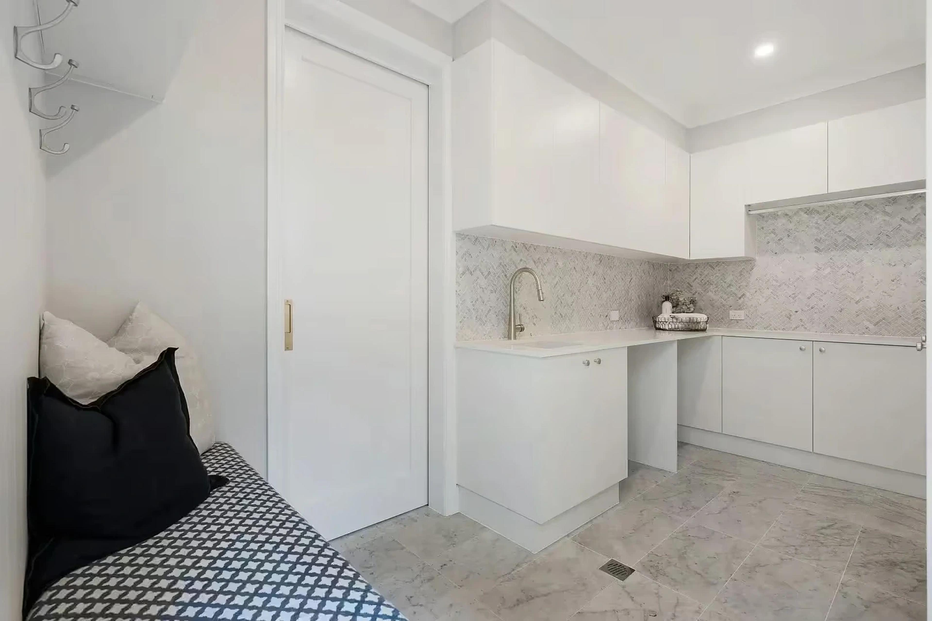 White laundry with marble splashback and tiled floor