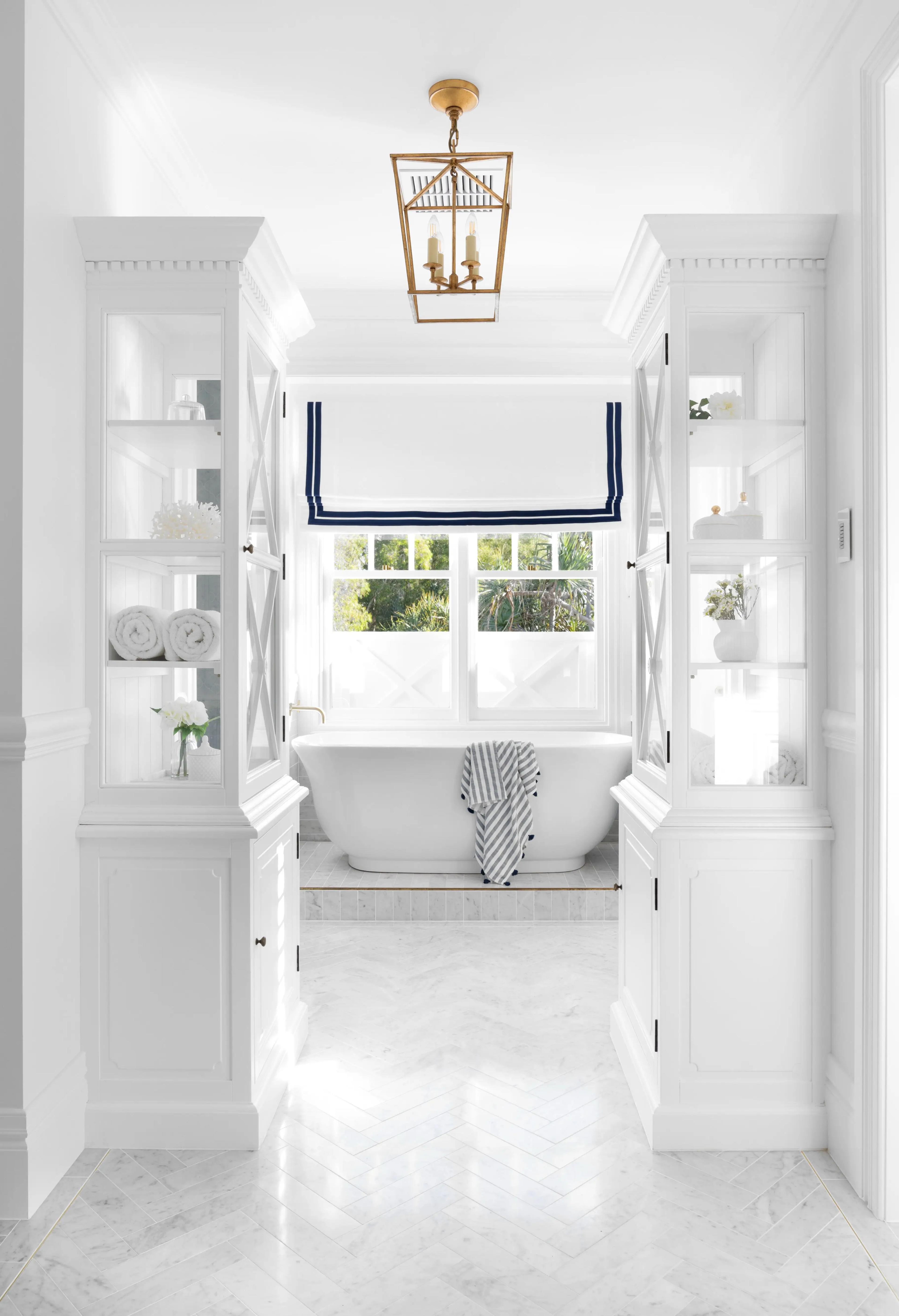 White ensuite with freestanding bath framed by glazed cabinetry