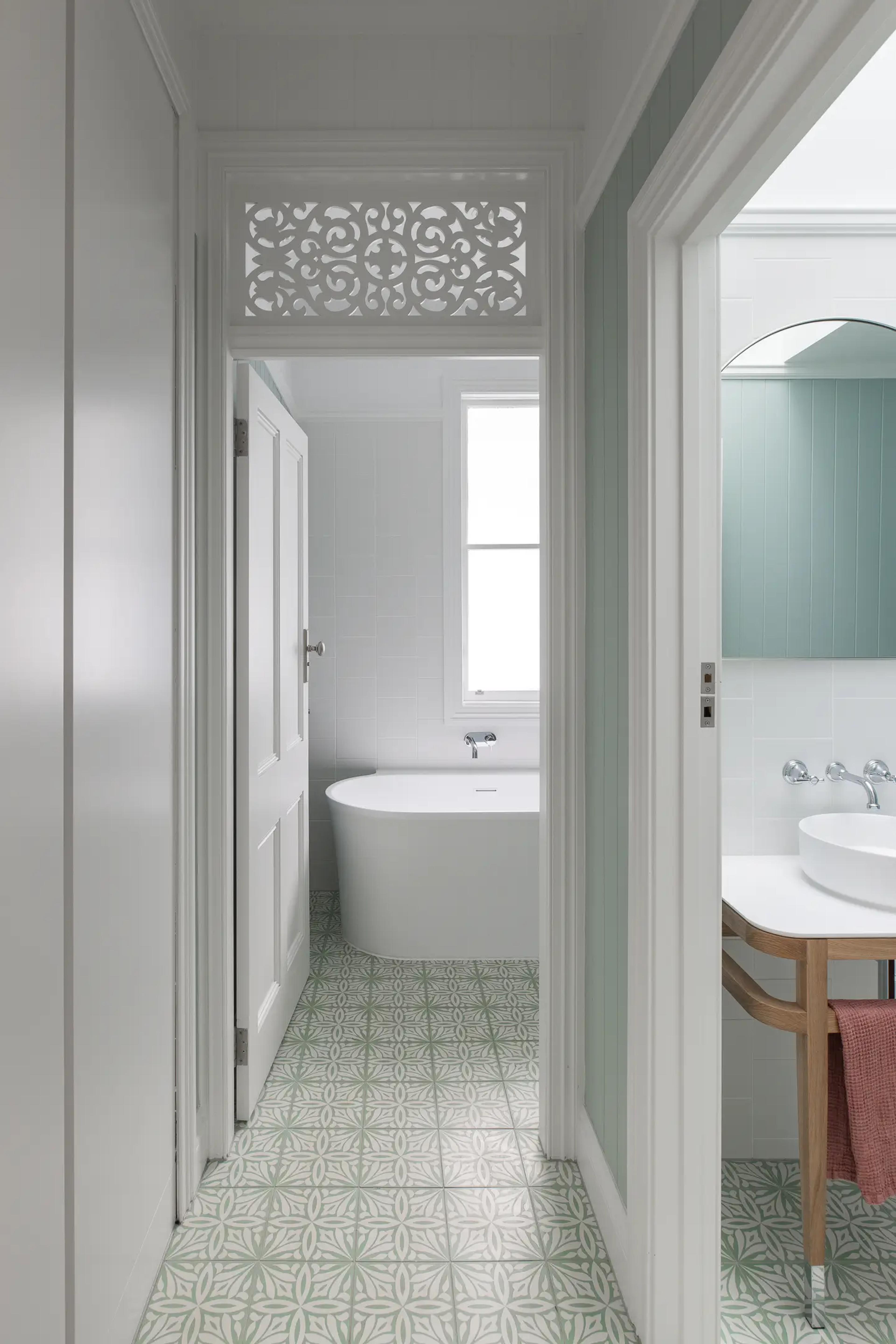 Bathroom with freestanding bath and patterned green floor tiles