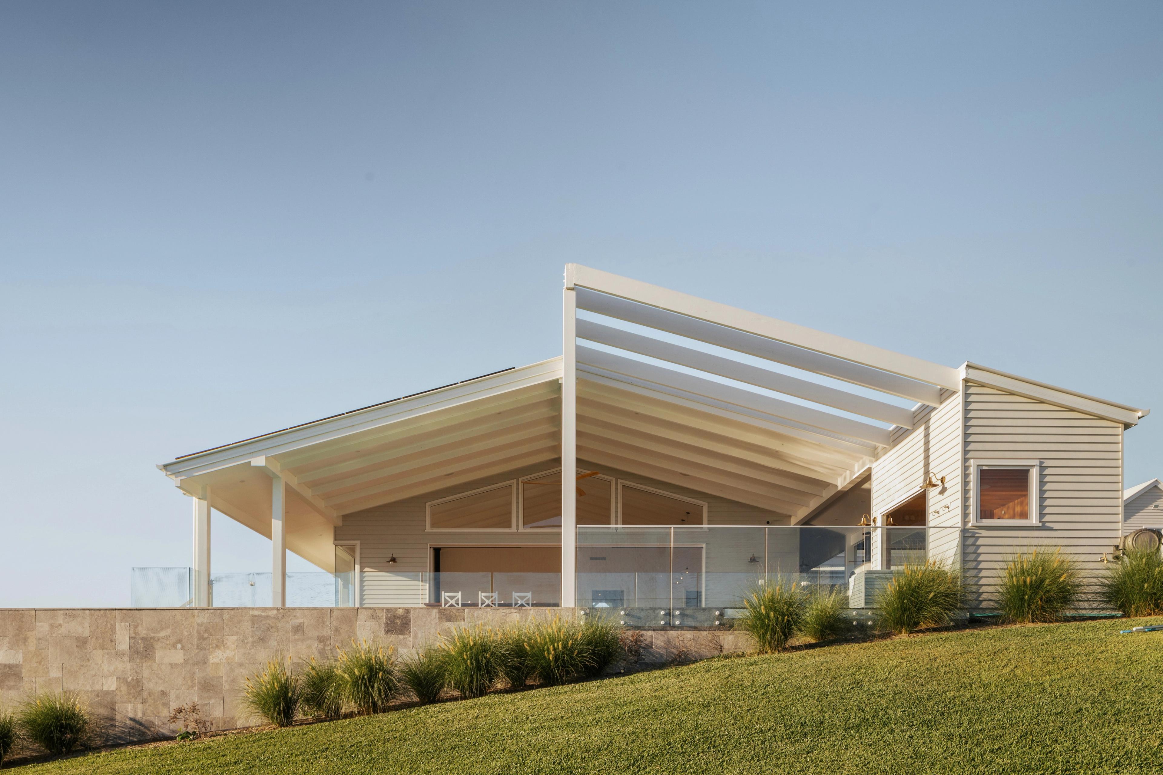 Angled roofline of verandah with glass balustrade above stone wall