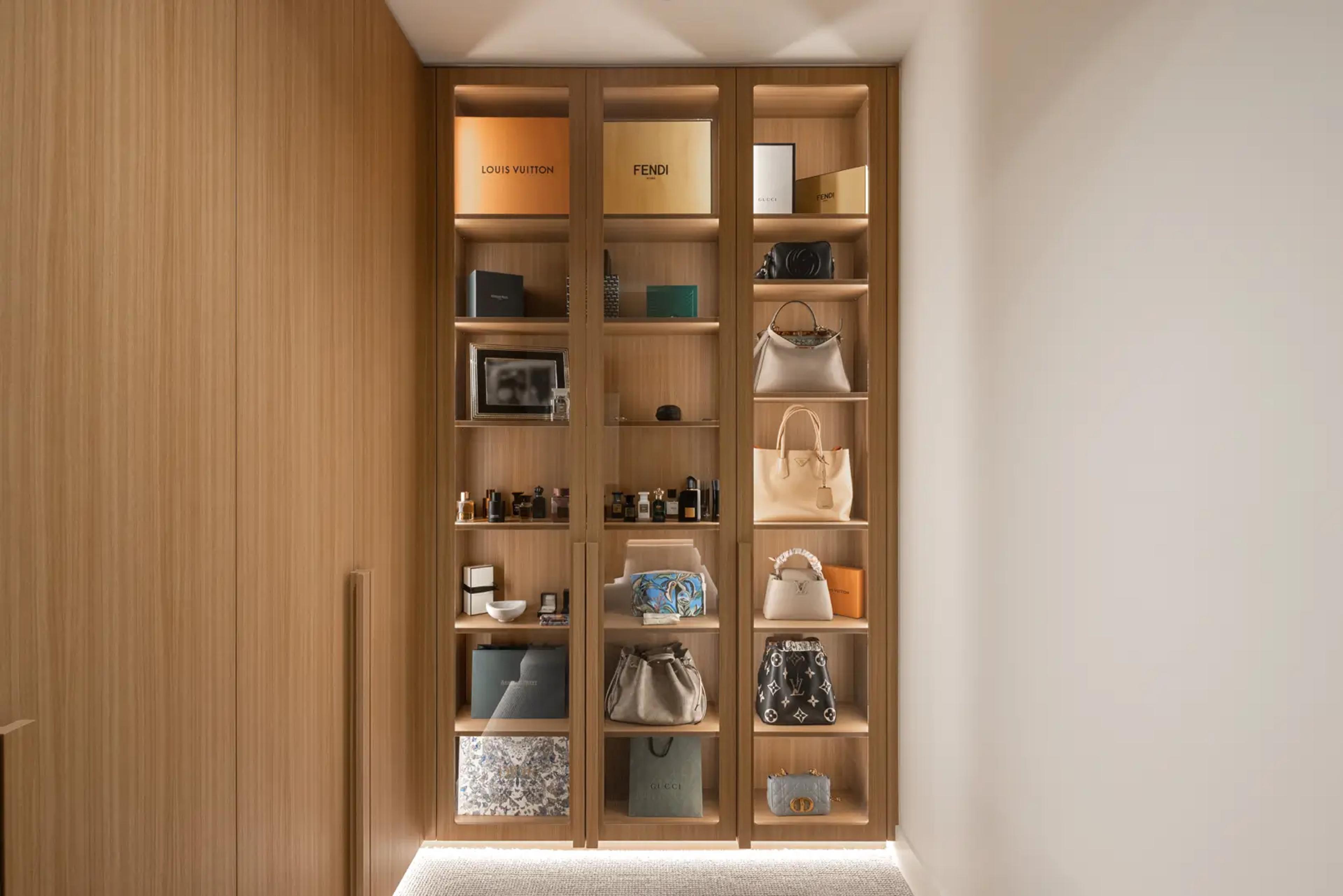 Walk in wardrobe with lit timber shelving and handbags