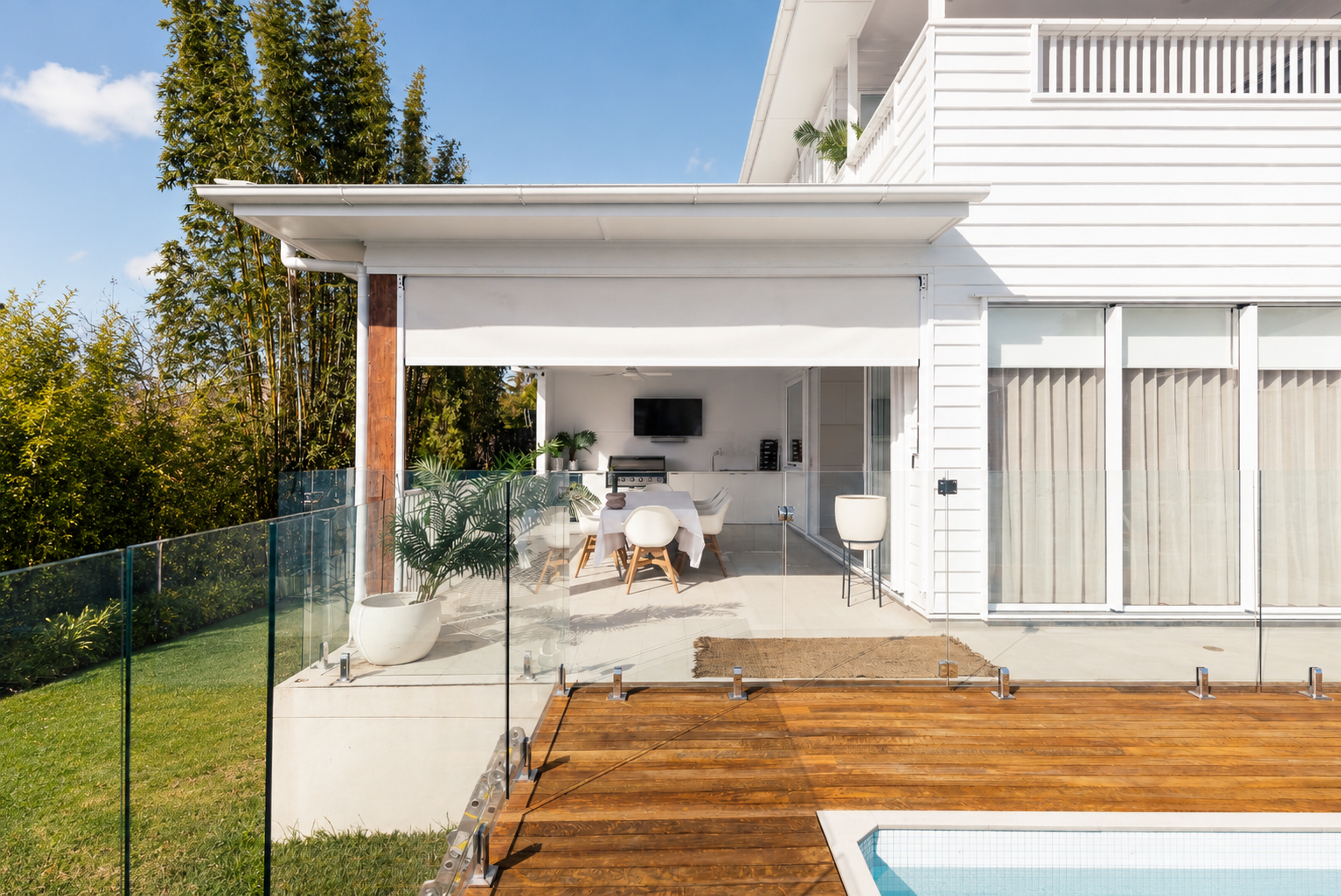 Covered terrace and timber pool deck at the rear of the white weatherboard home