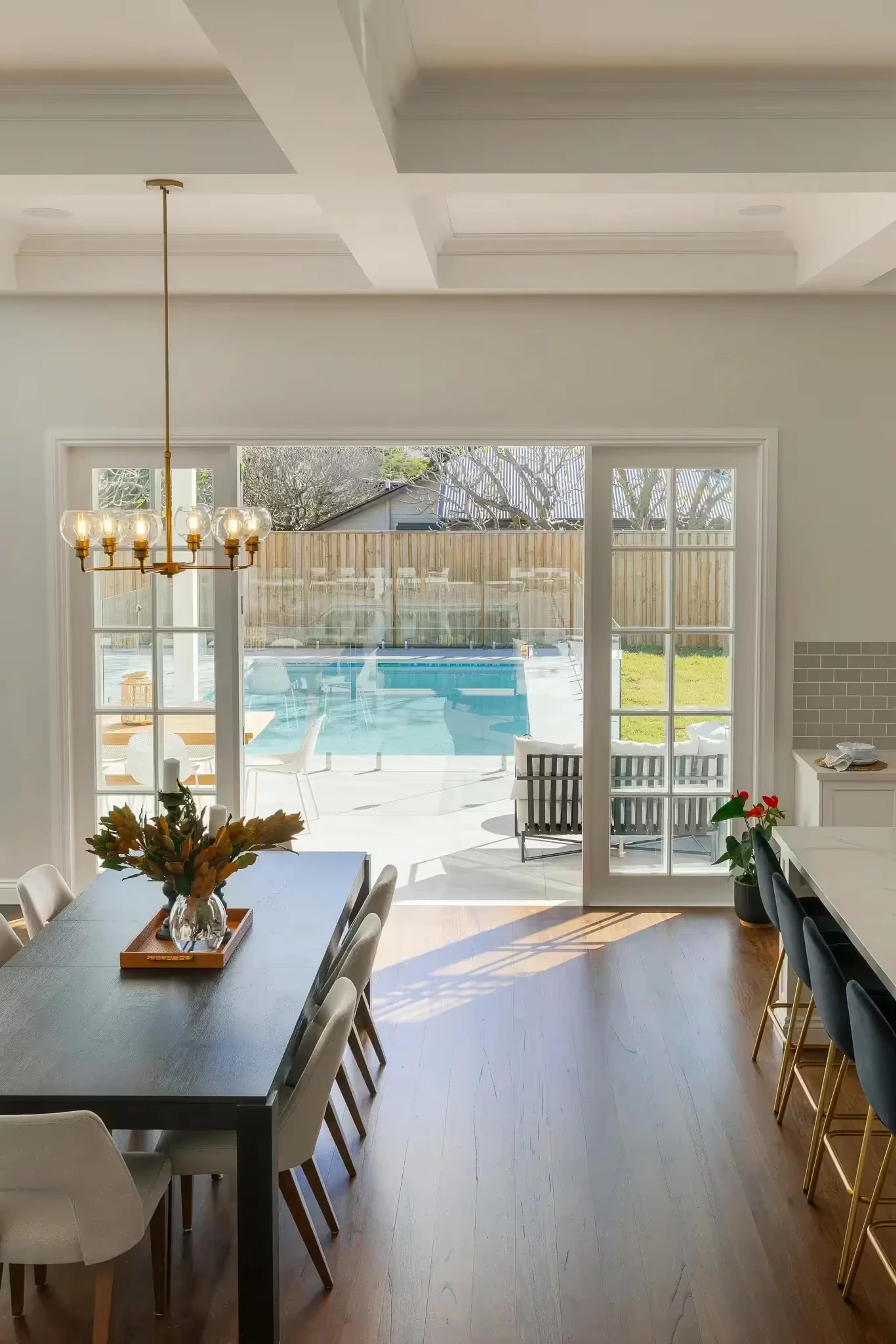 Dining room with dark timber table facing pool through glass doors