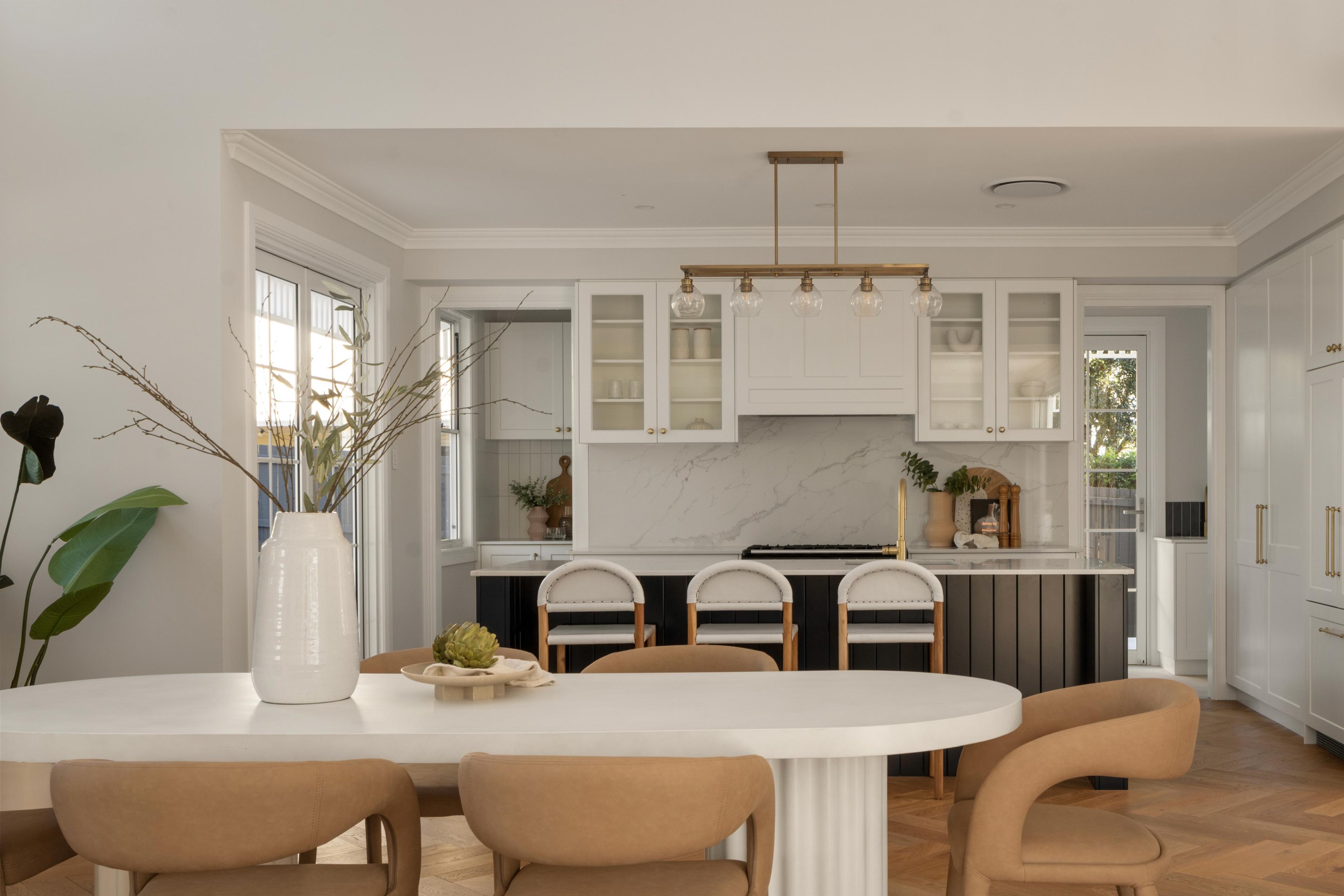 White kitchen with marble splashback and oval dining table